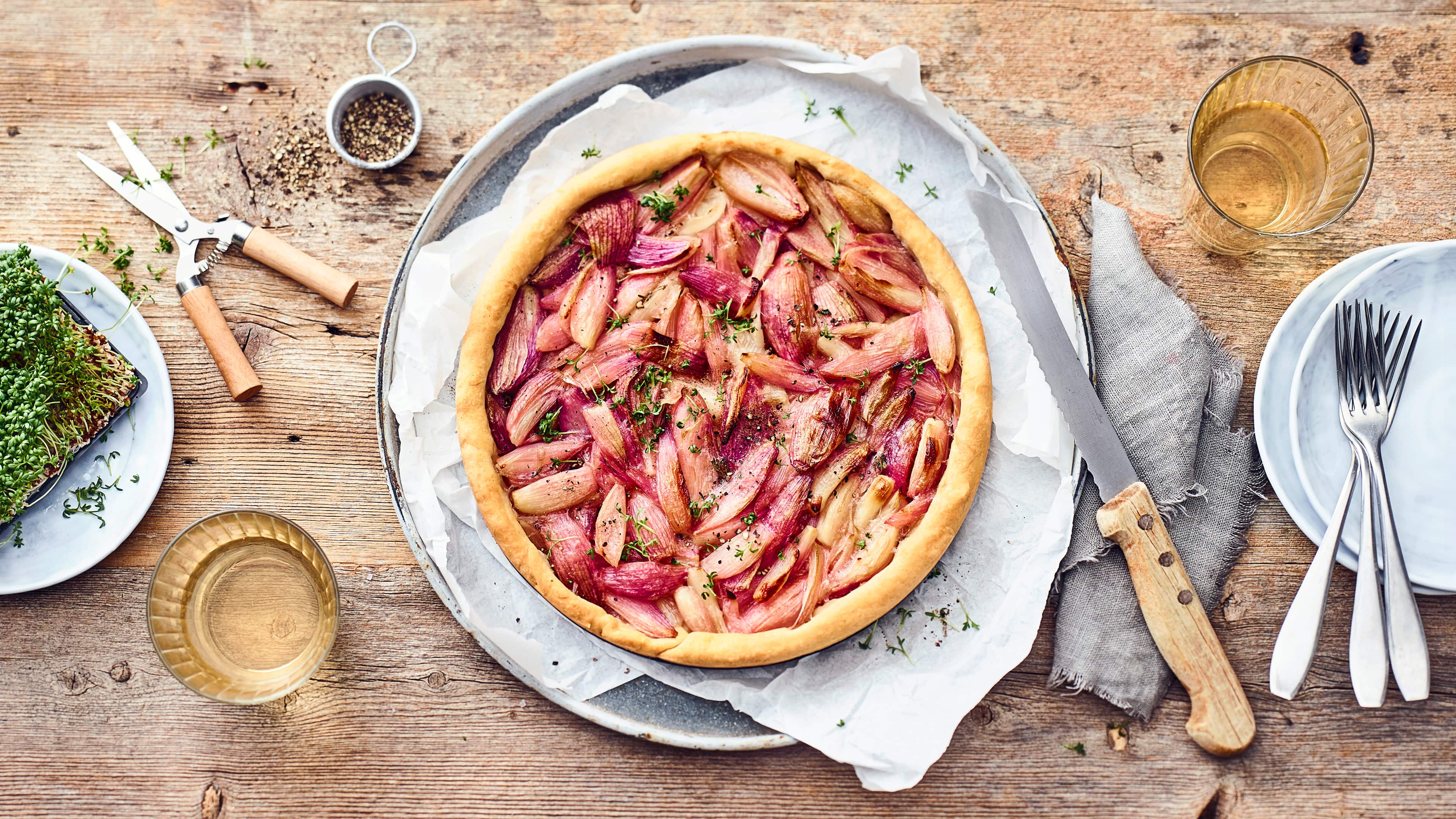 Zwiebelkuchen Unser Rezept für Zwiebelkuchen besticht mit einem knusprigen Hefeteig sowie einem leicht süßlichen Belag aus Schalotten, die vorher mit Weißwein und Balsamico abgelöscht werden.