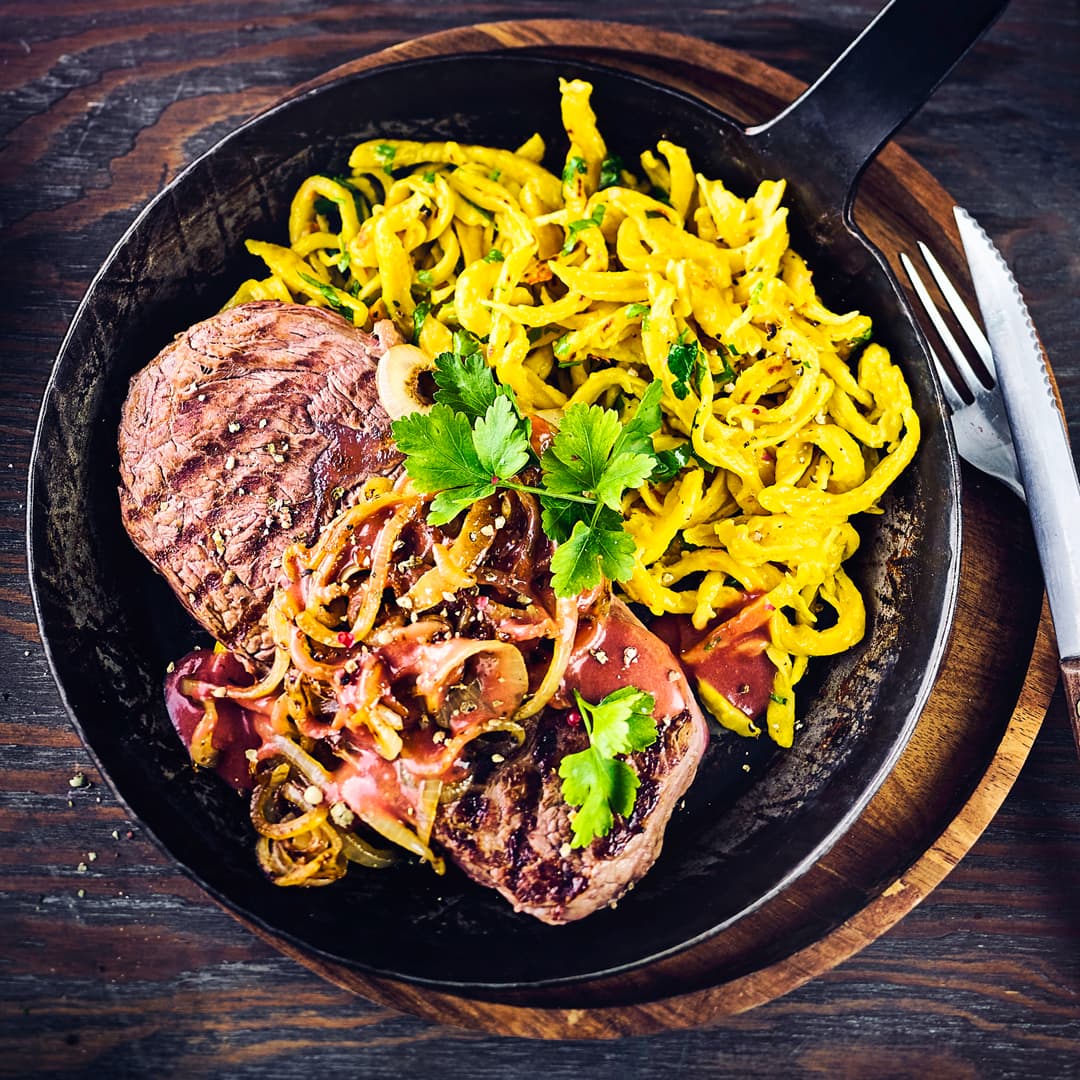 Probieren Sie unser laktosefreies Rezept für Zwiebelrostbraten: Mit saftigem Rumpsteak, feinwürzigem Sauerkraut und raffinierten Kürbis-Kräuterspätzle!