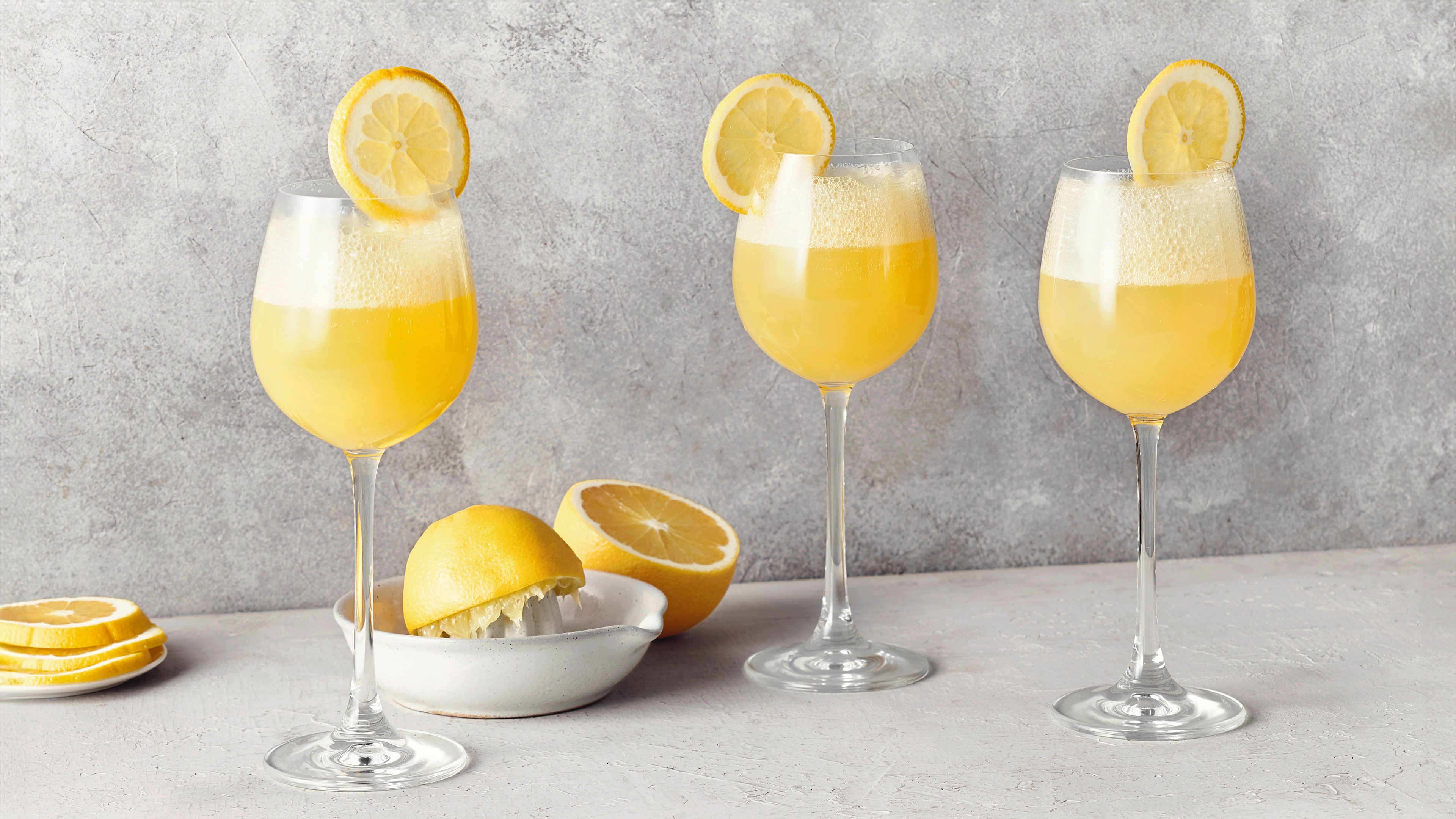 Ein Glas mit gelbem Zitronensaft, garniert mit einer dünnen Zitronenscheibe am Rand