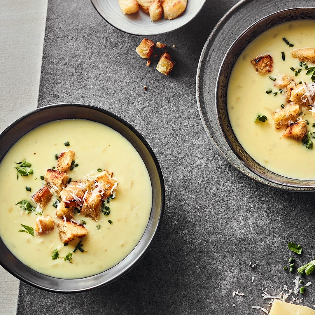 Schälchen mit cremiger, käsiger Suppe, getoppt mit knusprigen Croûtons, frischem Schnittlauch und frischer Petersilie