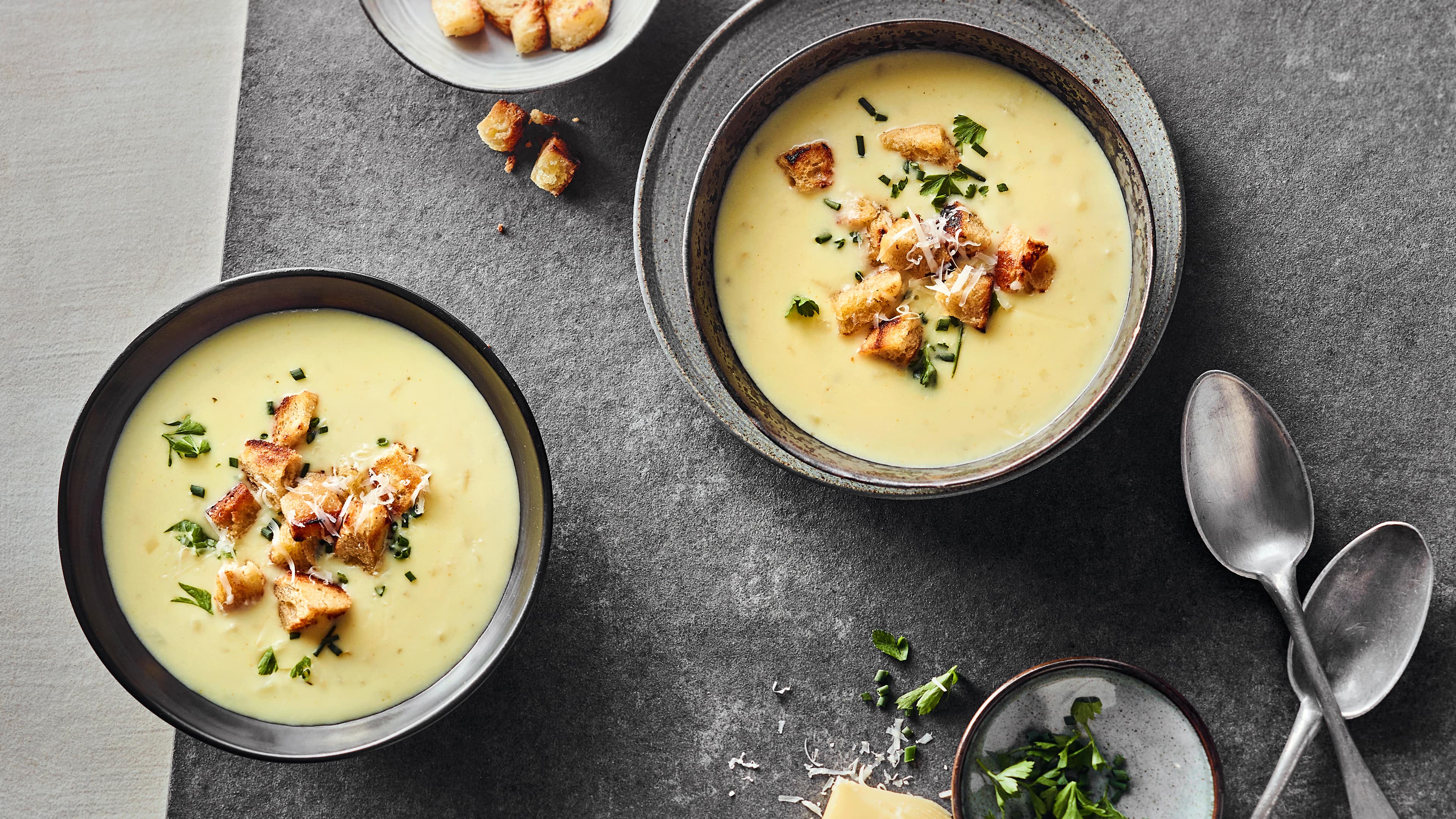 Rezept für Allgäuer Käsesuppe Schälchen mit cremiger, käsiger Suppe, getoppt mit knusprigen Croûtons, frischem Schnittlauch und frischer Petersilie