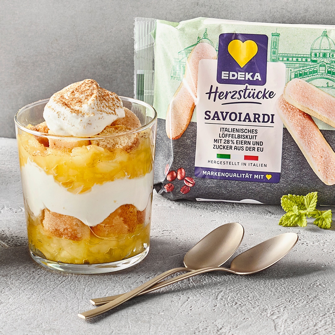 Schichtdessertglas mit abwechselnder Apfelschicht und weißer Creme. Rechts daneben EDEKA Herzstücke Savoiardi (Löffelbiscuits).