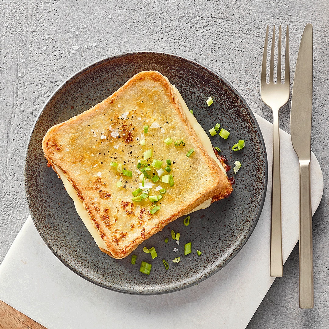 Knusprige Toastscheiben mit Käsescheibe, garniert mit Schnittlauchstücken