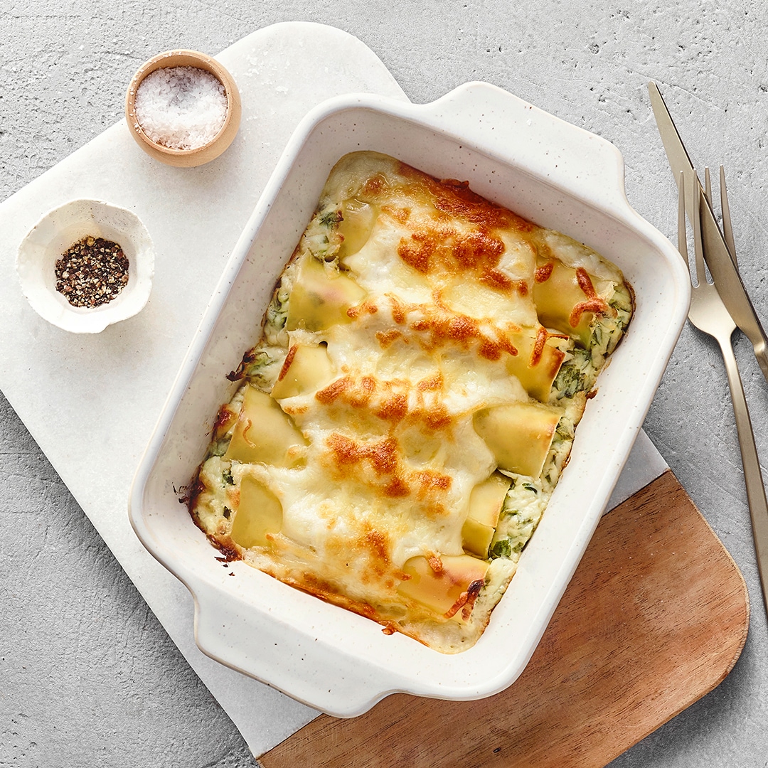 Mit Käse überbackene Cannelloni mit glatter, heller Oberfläche, durch die eine grüne Bärlauchfüllung leicht durchschimmert.