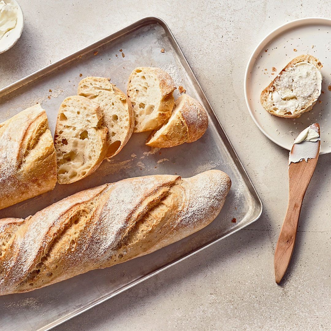 Helles, längliches Brot mit einem luftigen, fluffigen Teig und einer knusprigen Kruste, auf einem Backblech
