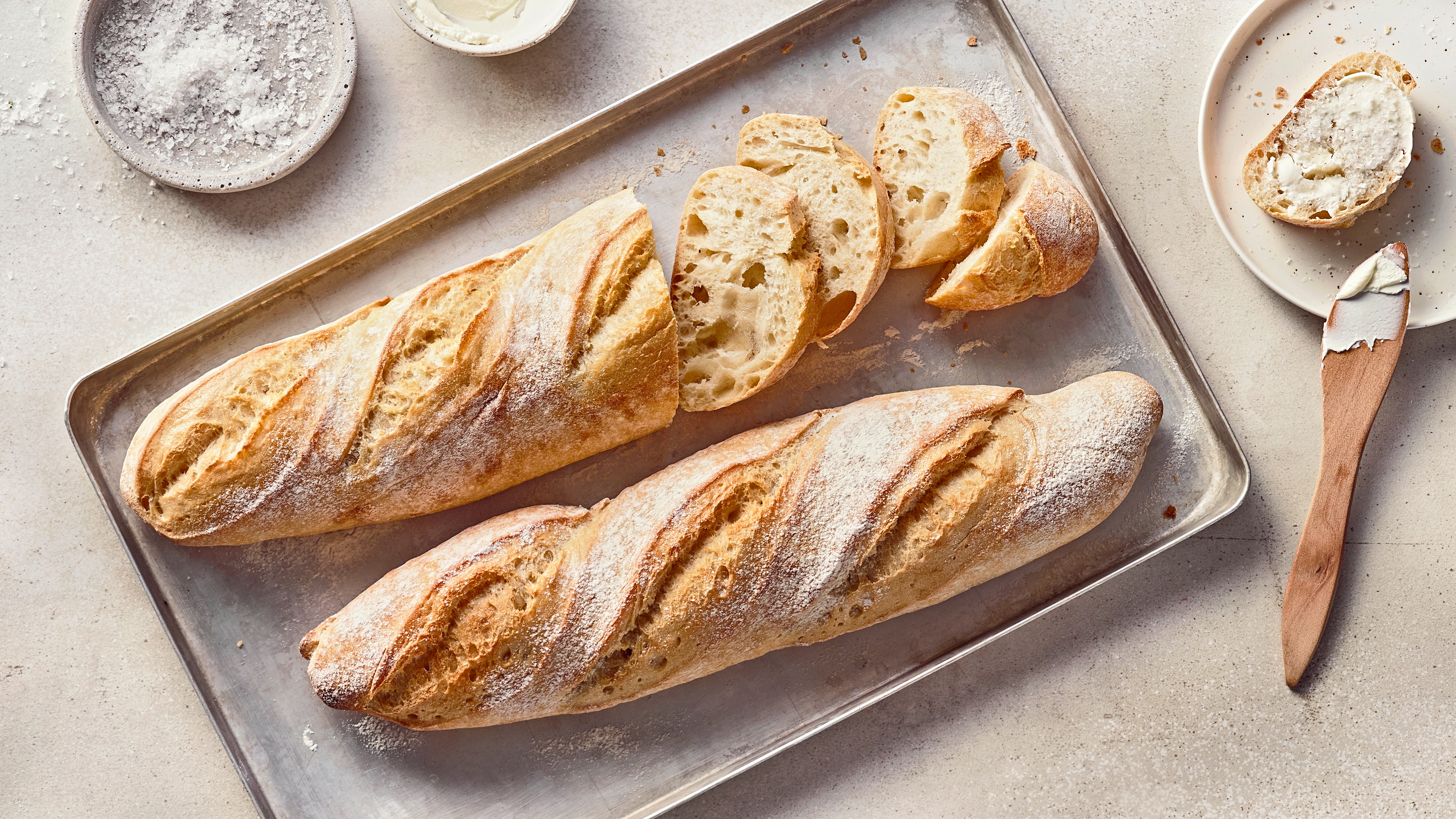 Rezept für Baguette magique Helles, längliches Brot mit einem luftigen, fluffigen Teig und einer knusprigen Kruste, auf einem Backblech