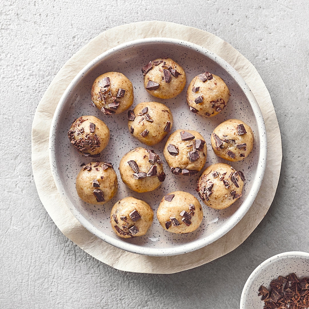 Schale mit mehreren rohen Teilbällchen mit Schokoladenstücken.