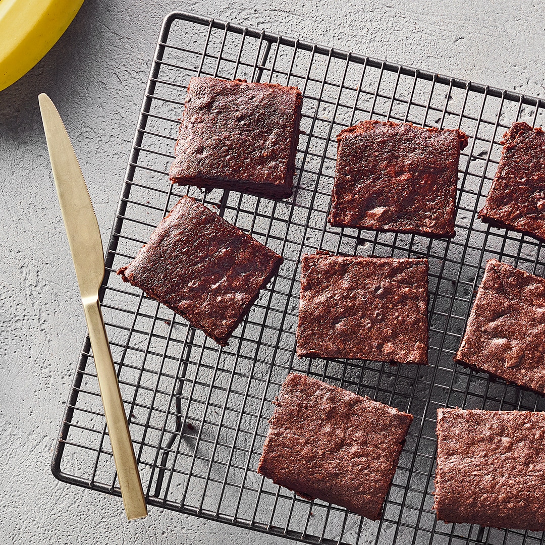 Ein Gitter mit acht quadratischen, dunkelbraunen, fluffig gebackenen Stücken Gebäck.