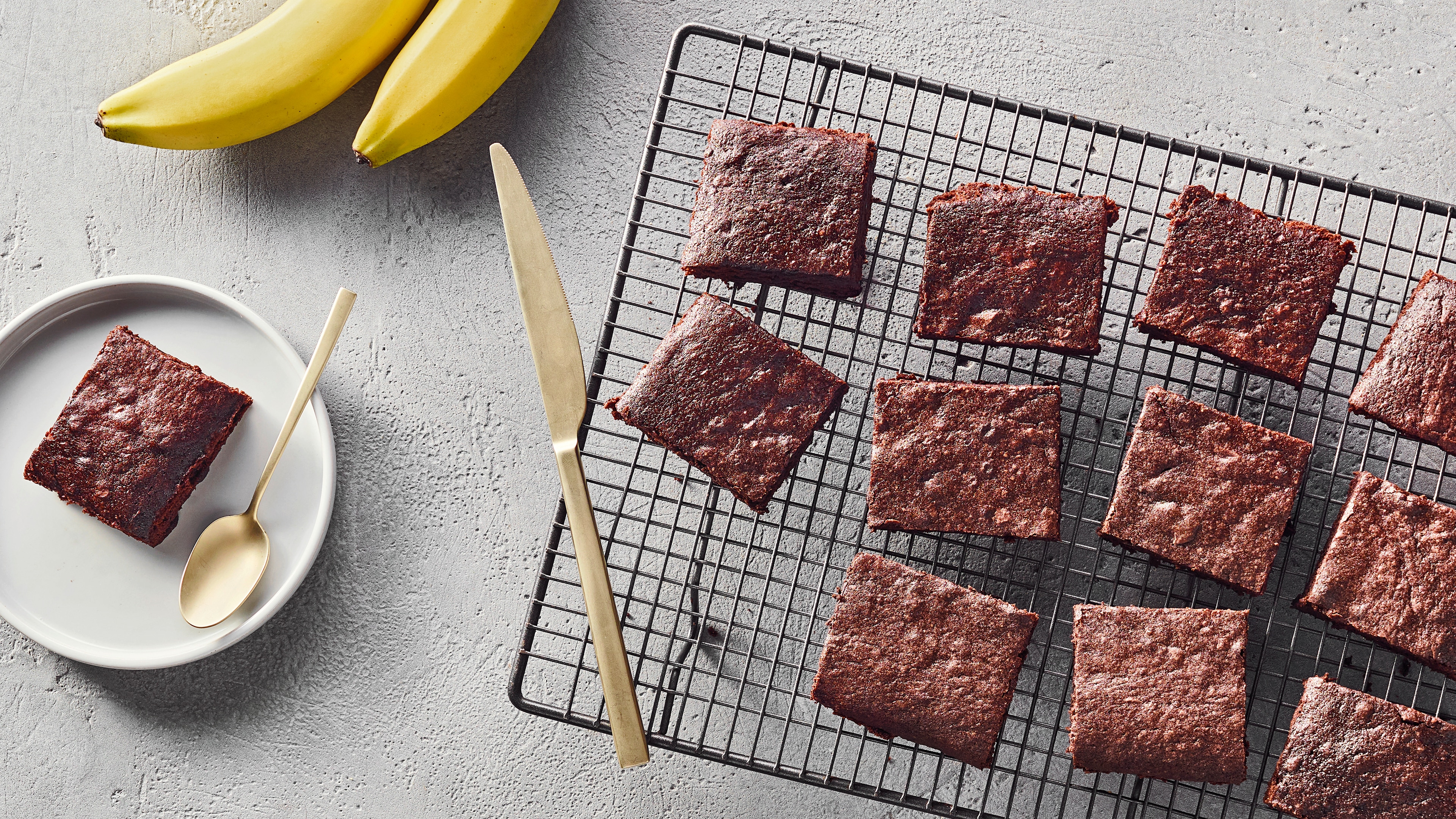 Ein Gitter mit acht quadratischen, dunkelbraunen, fluffig gebackenen Stücken Gebäck.