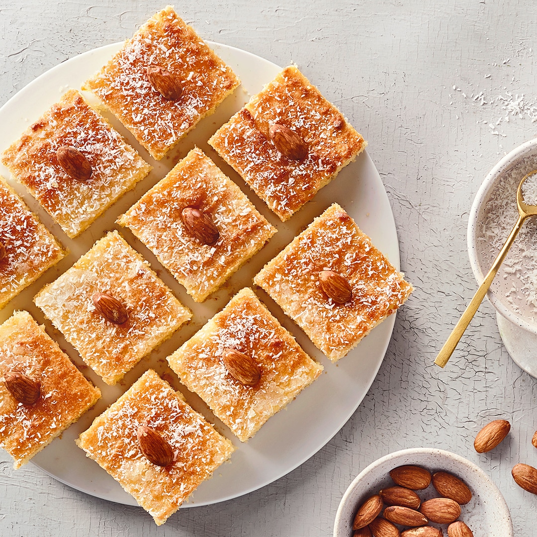 Teller mit Gebäck Quadraten, garniert mit Kokosraspeln und Mandeln.