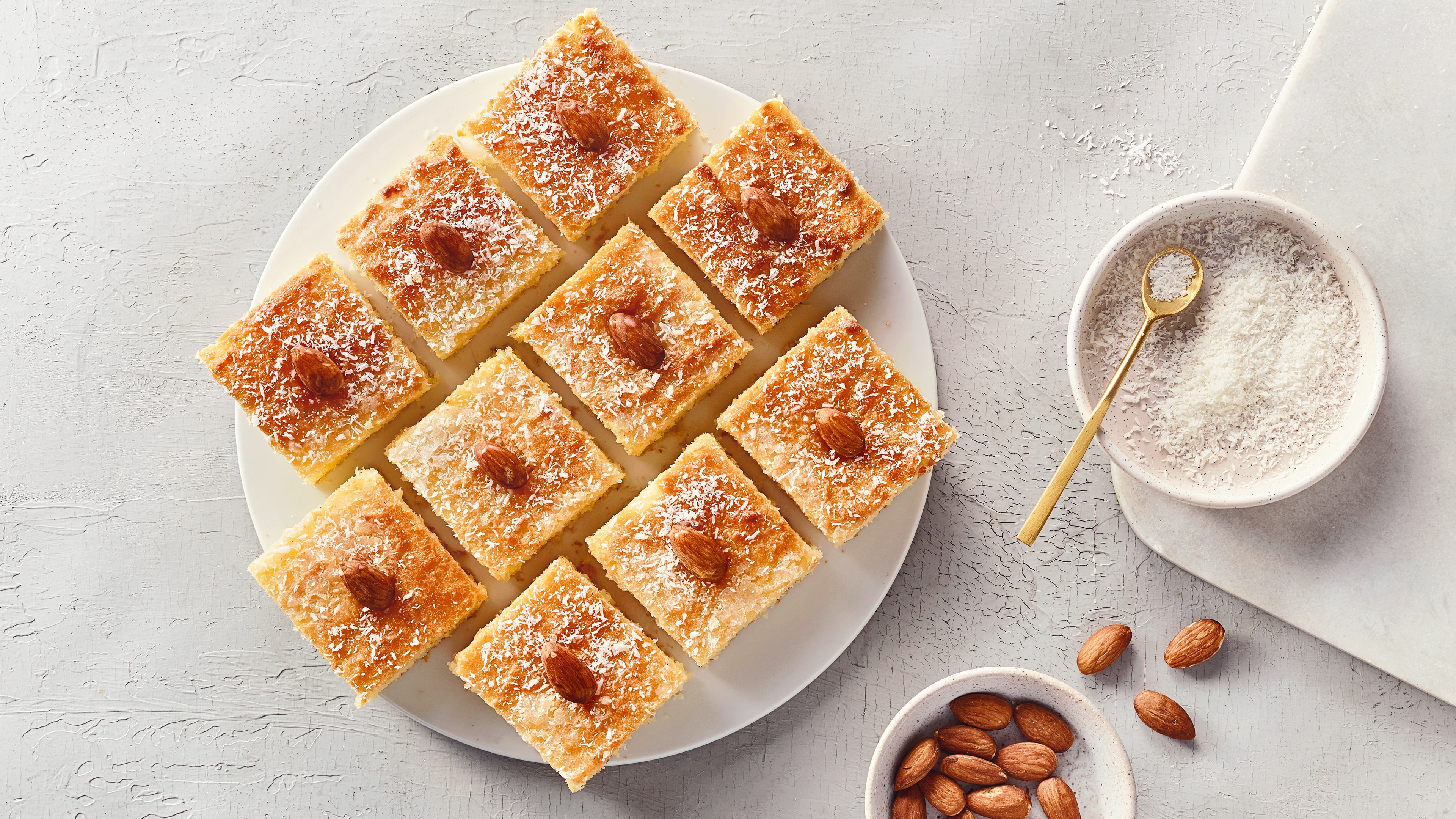 Teller mit Gebäck Quadraten, garniert mit Kokosraspeln und Mandeln.