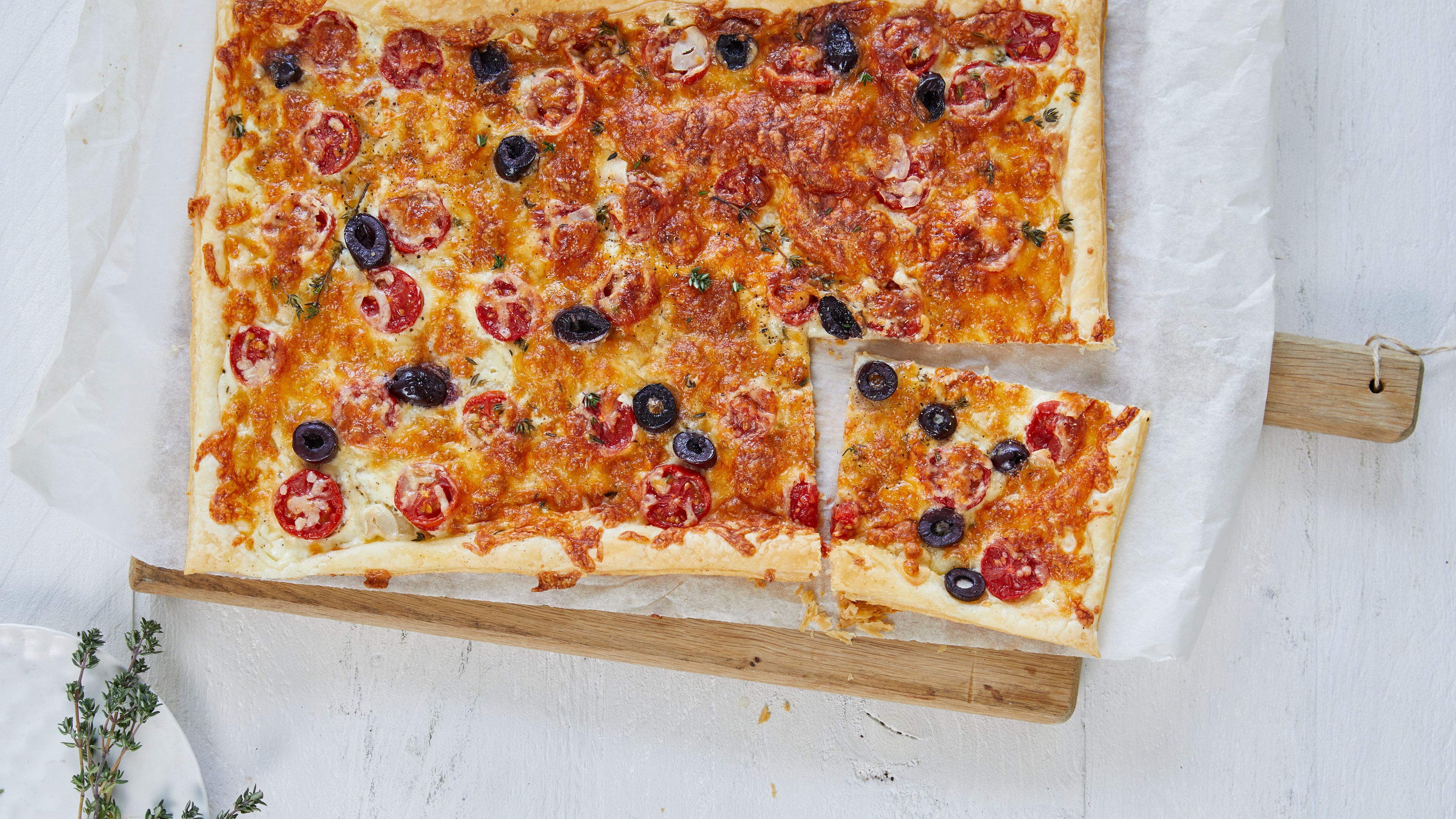 Pizza mit Tomatenscheiben und schwarzen Olivenscheiben