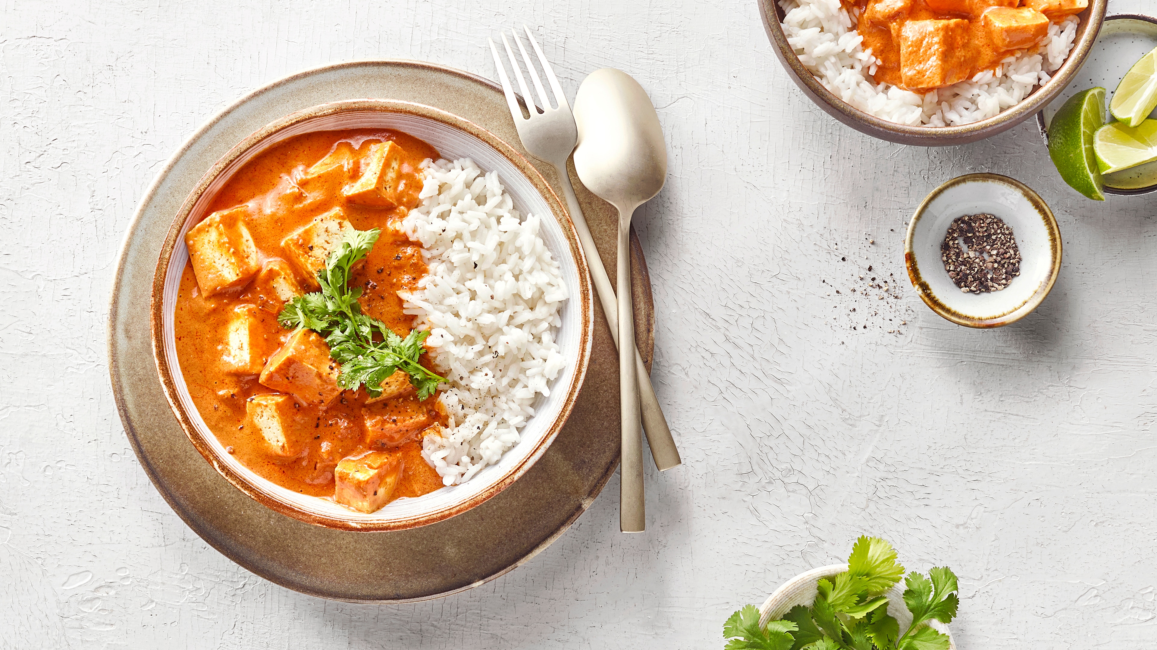 Schüssel mit Reis sowie Hähnchen mit einer cremigen Tomatensauce.