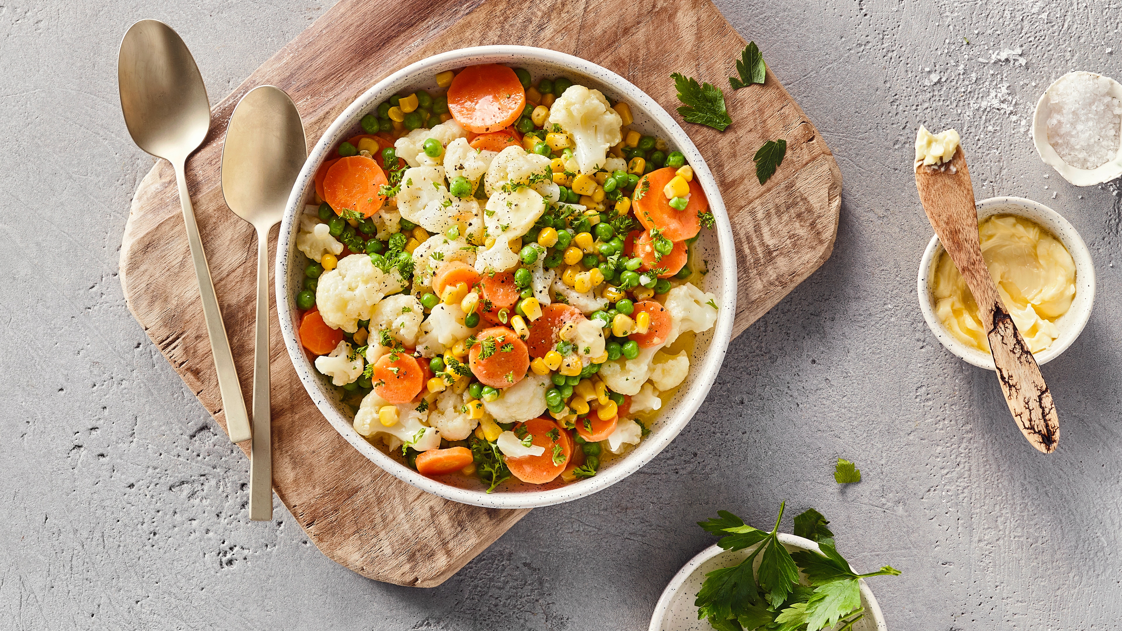 Schale mit Blumenkohlröschen, Möhrenscheiben, Erbsen und Mais. Mit Kräutern garniert.