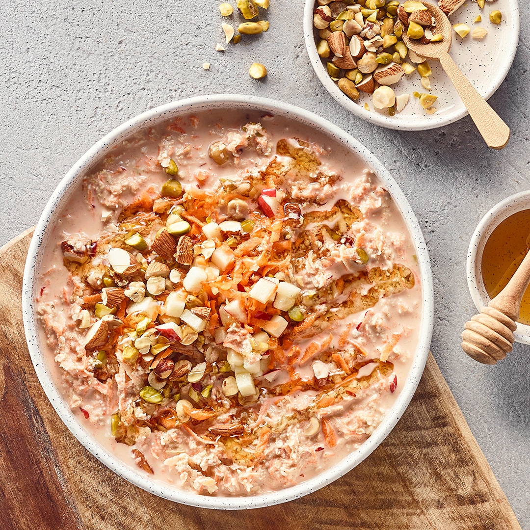 Schale mit Haferflocken in Flüssigkeit, getoppt mit Kernen und Möhrenstreifen