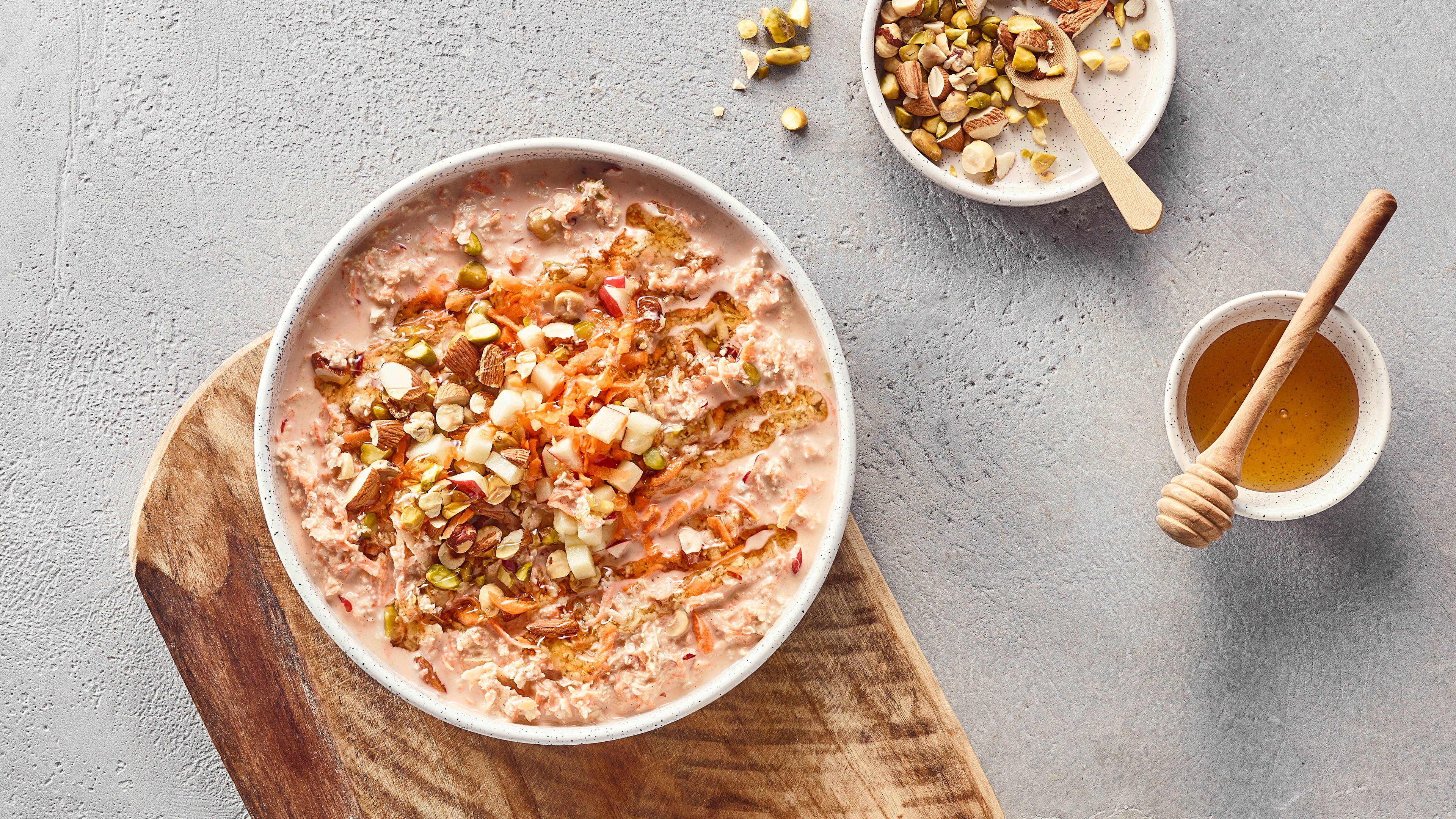 Schale mit Haferflocken in Flüssigkeit, getoppt mit Kernen und Möhrenstreifen