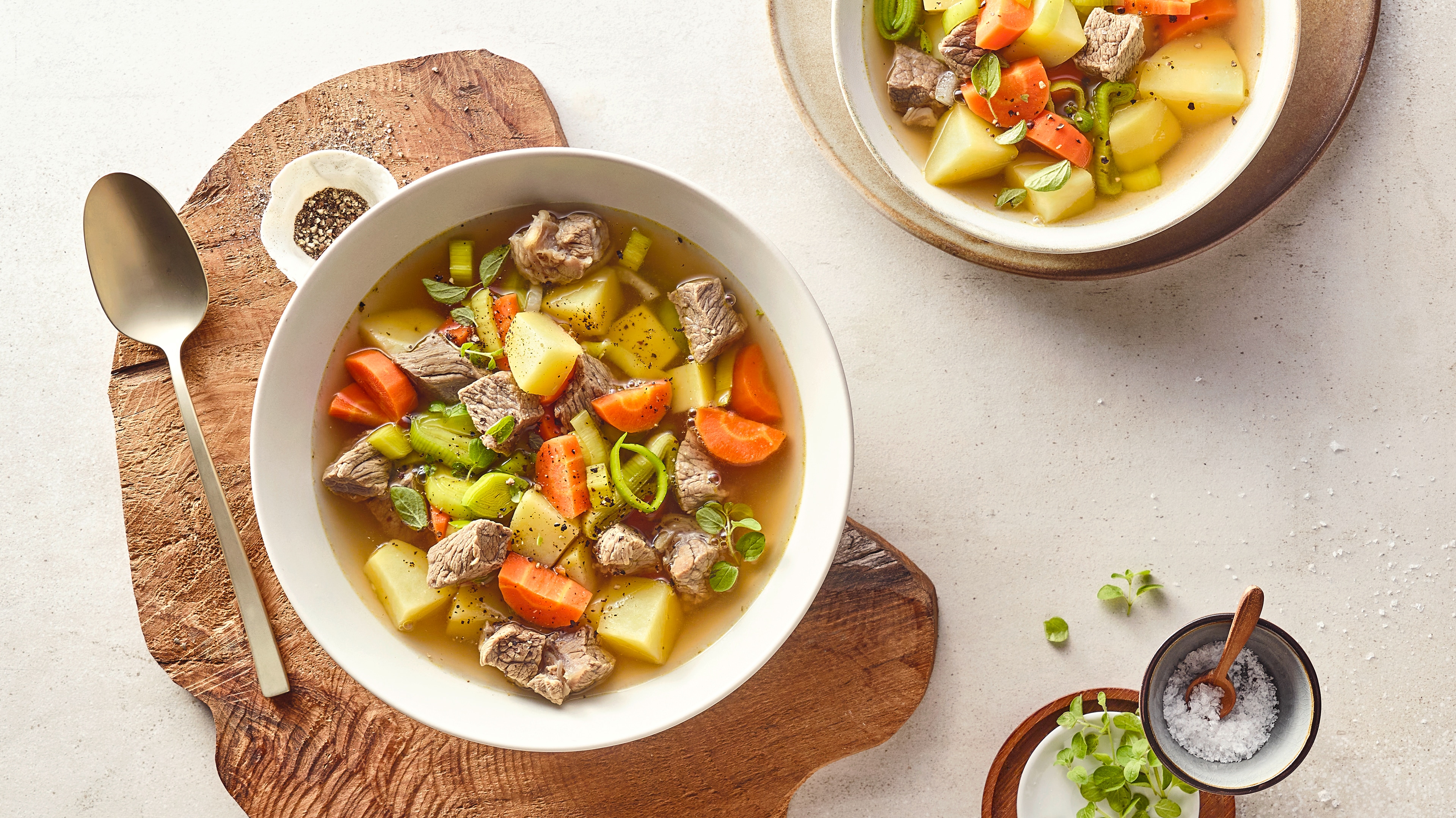 2 tiefe Teller mit Kartoffel-, Möhren und Fleischstücken in Brühe