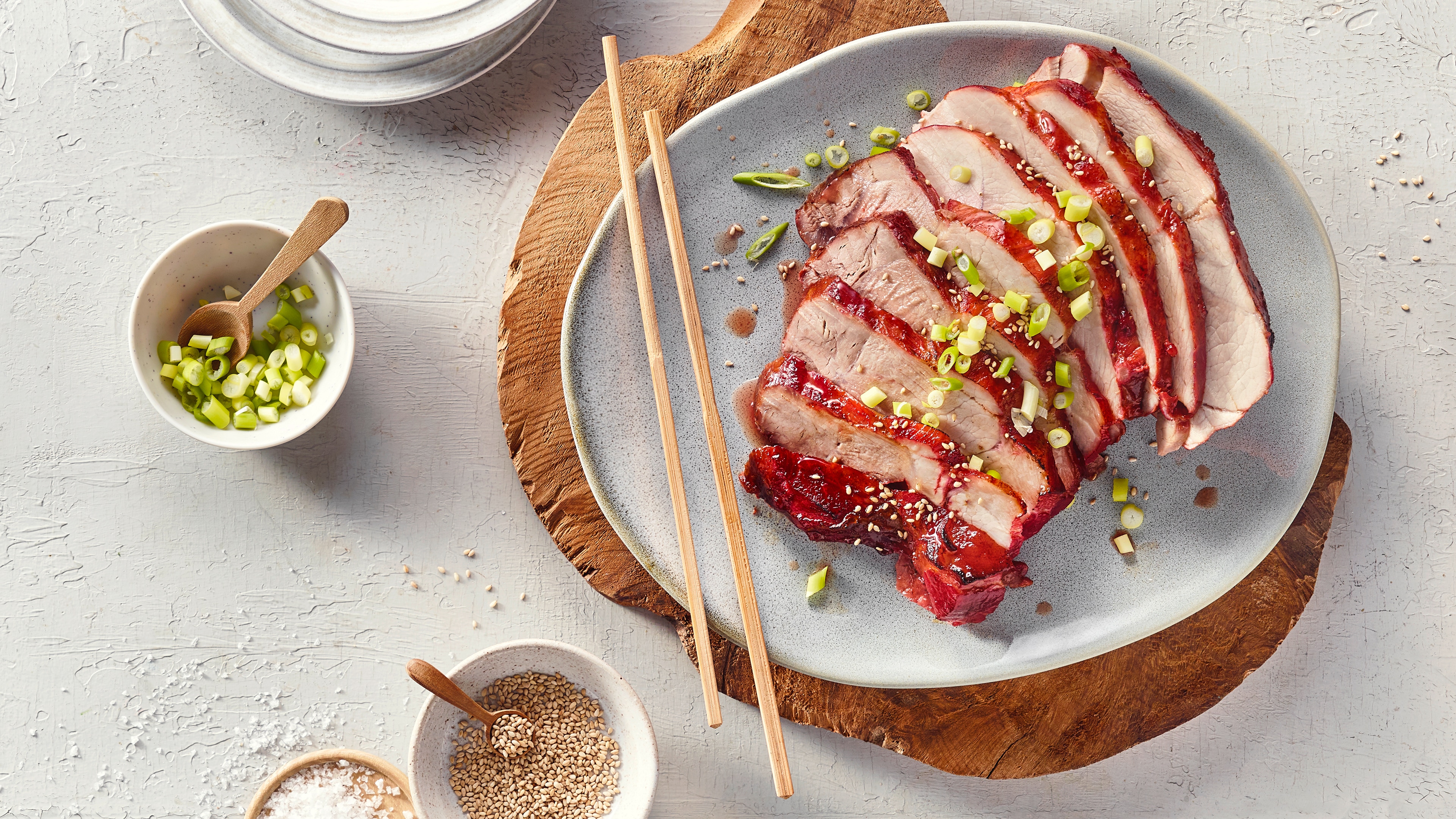 Teller mit geschnittenen und glasierten Fleischscheiben und Frühlingszwiebelringen