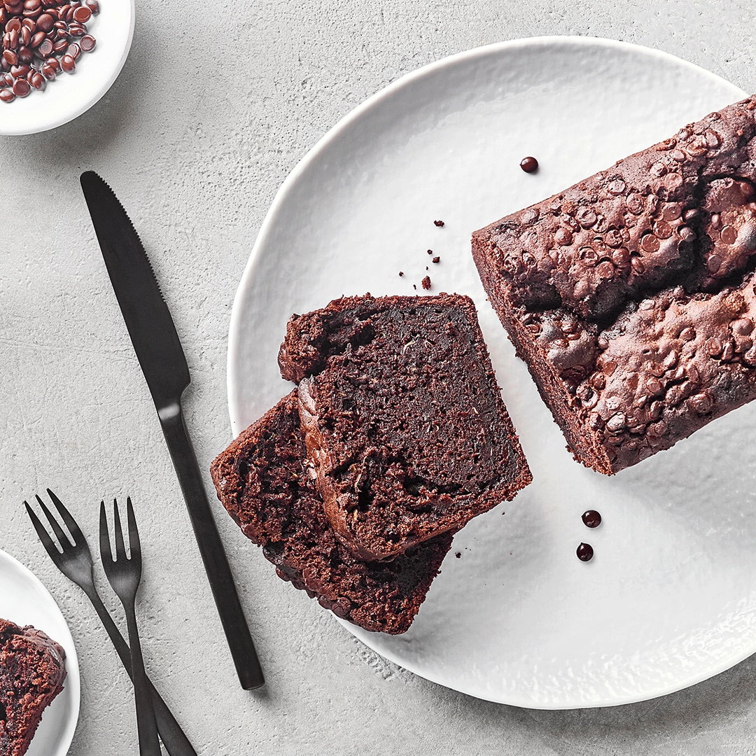Schokoladenkuchen mit angeschnittenen Scheiben auf weißem Teller, dekoriert mit Kaffeebohnen.