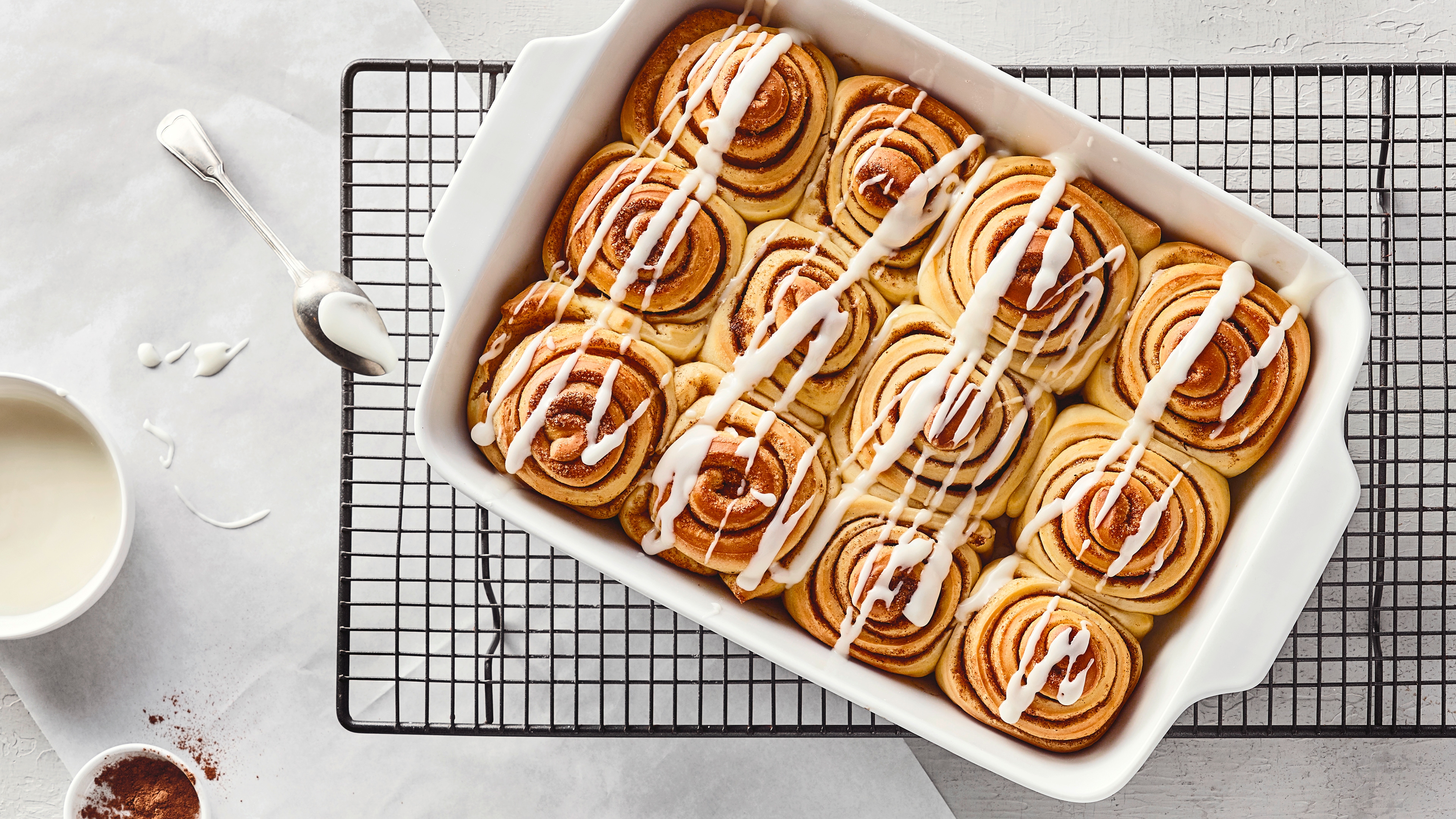 Rezept für Cinnamon Rolls Eine Auflaufform mit fluffigen Teigschnecken mit einer Zimt-Zucker-Füllung, garniert mit weißer Zuckerguss