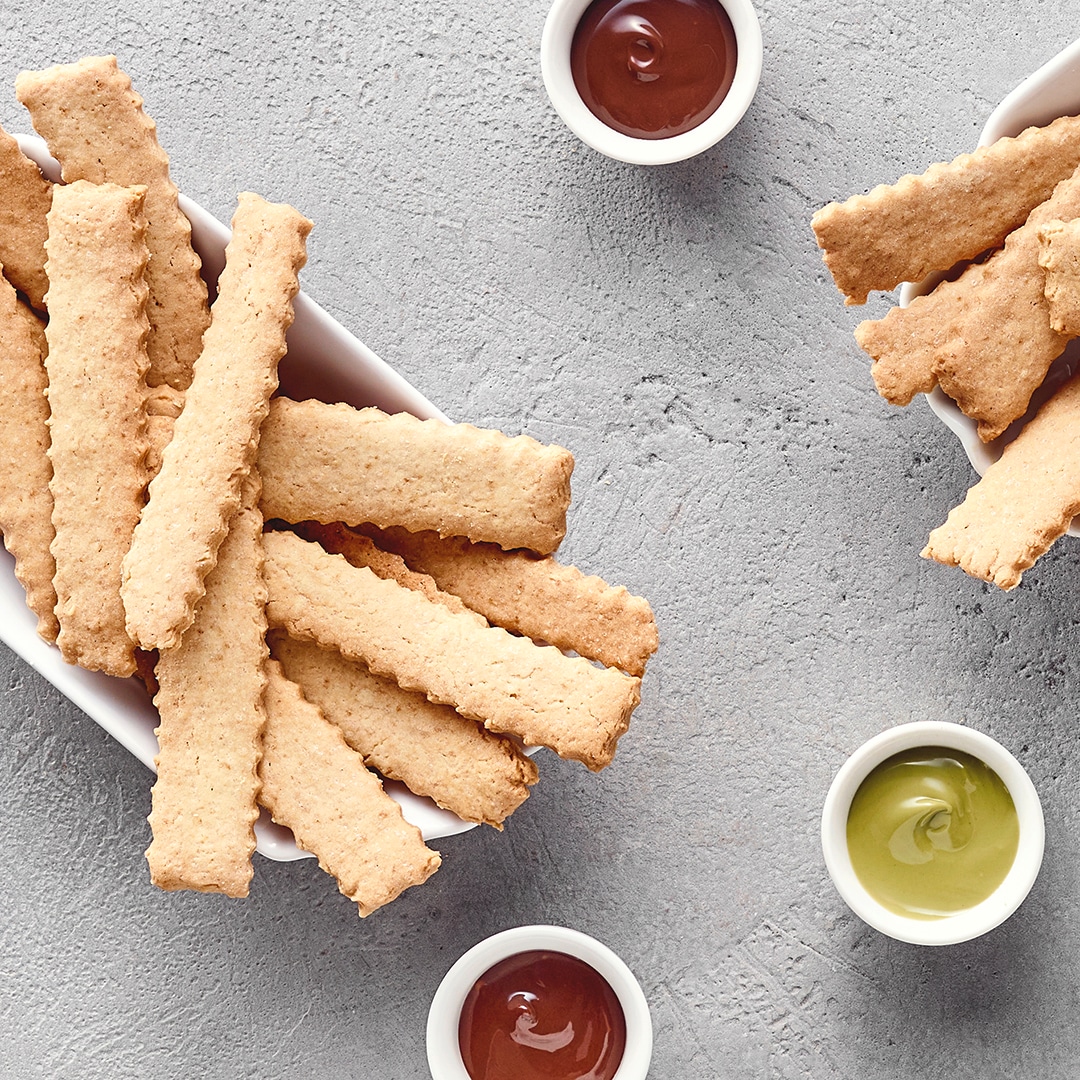 In Streifen geschnittene, goldbraune Cookie‑Sticks, serviert wie Pommes in kleinen Schalen.