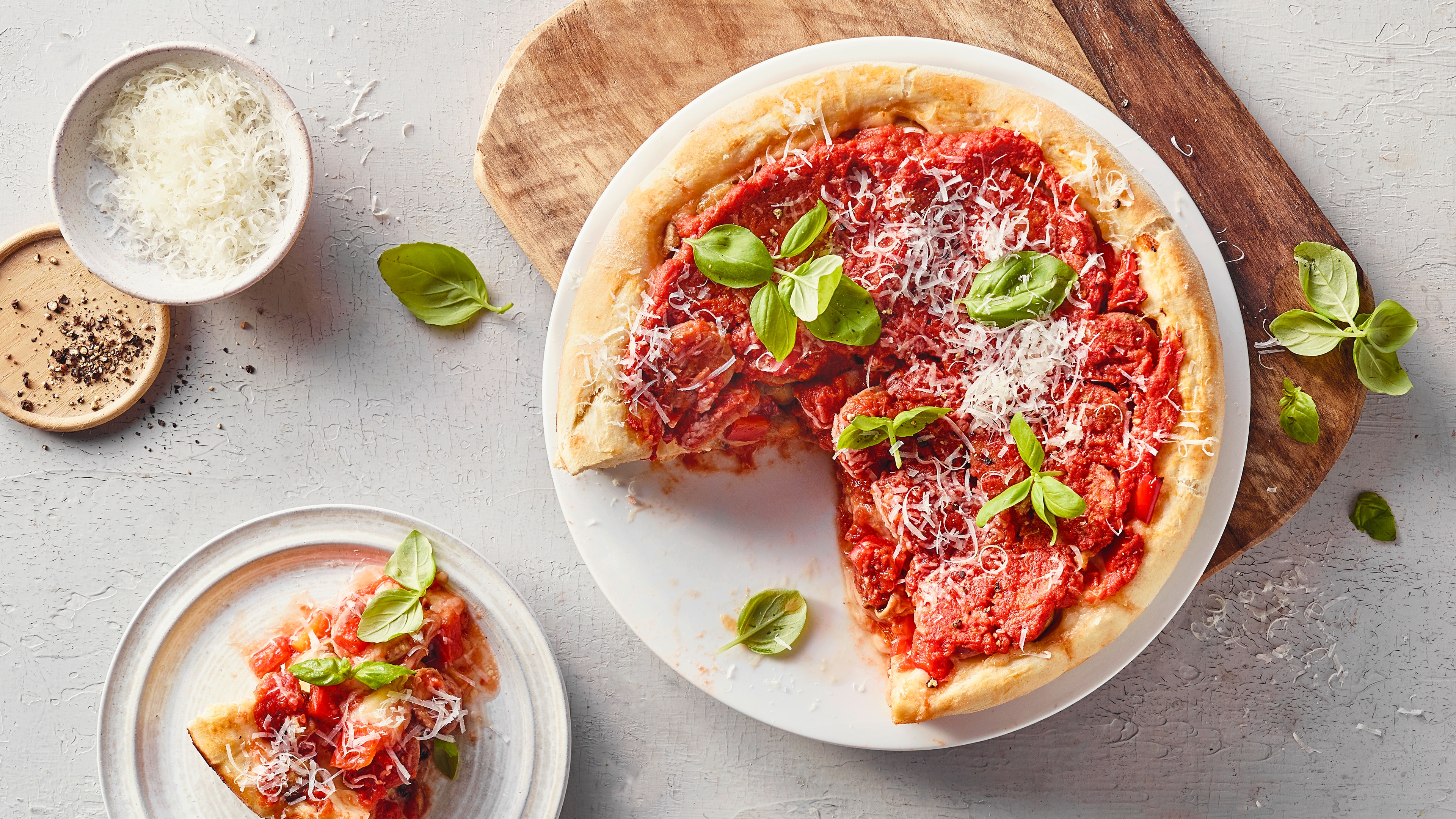 Ein Teller mit einer Pizza, bedeckt mit Tomatensauce, garniert mit grünen Basilikumblättern und feinem geriebenem Käse