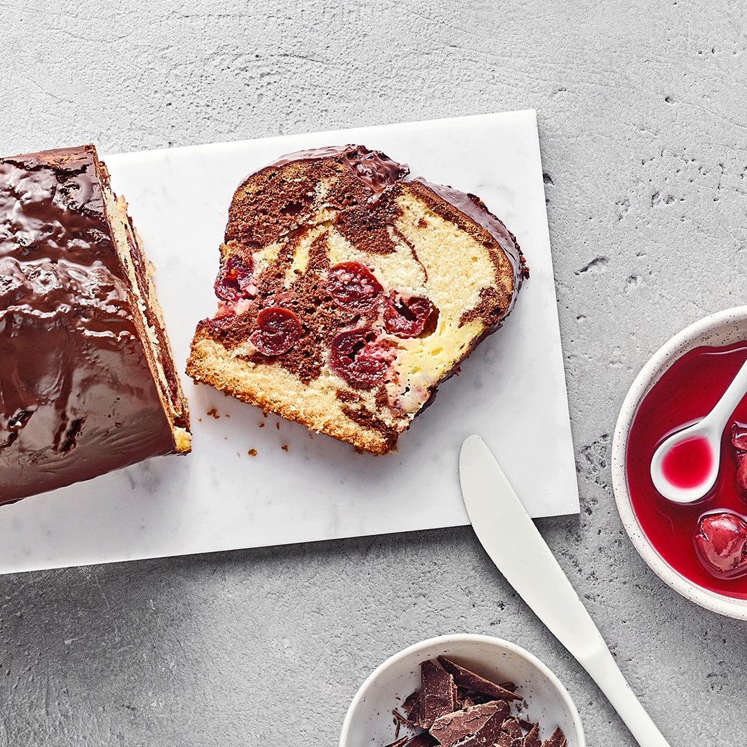 Kastenkuchen aus hellem und dunklem Rührteig und Sauerkirschen, überzogen mit Schokolade.