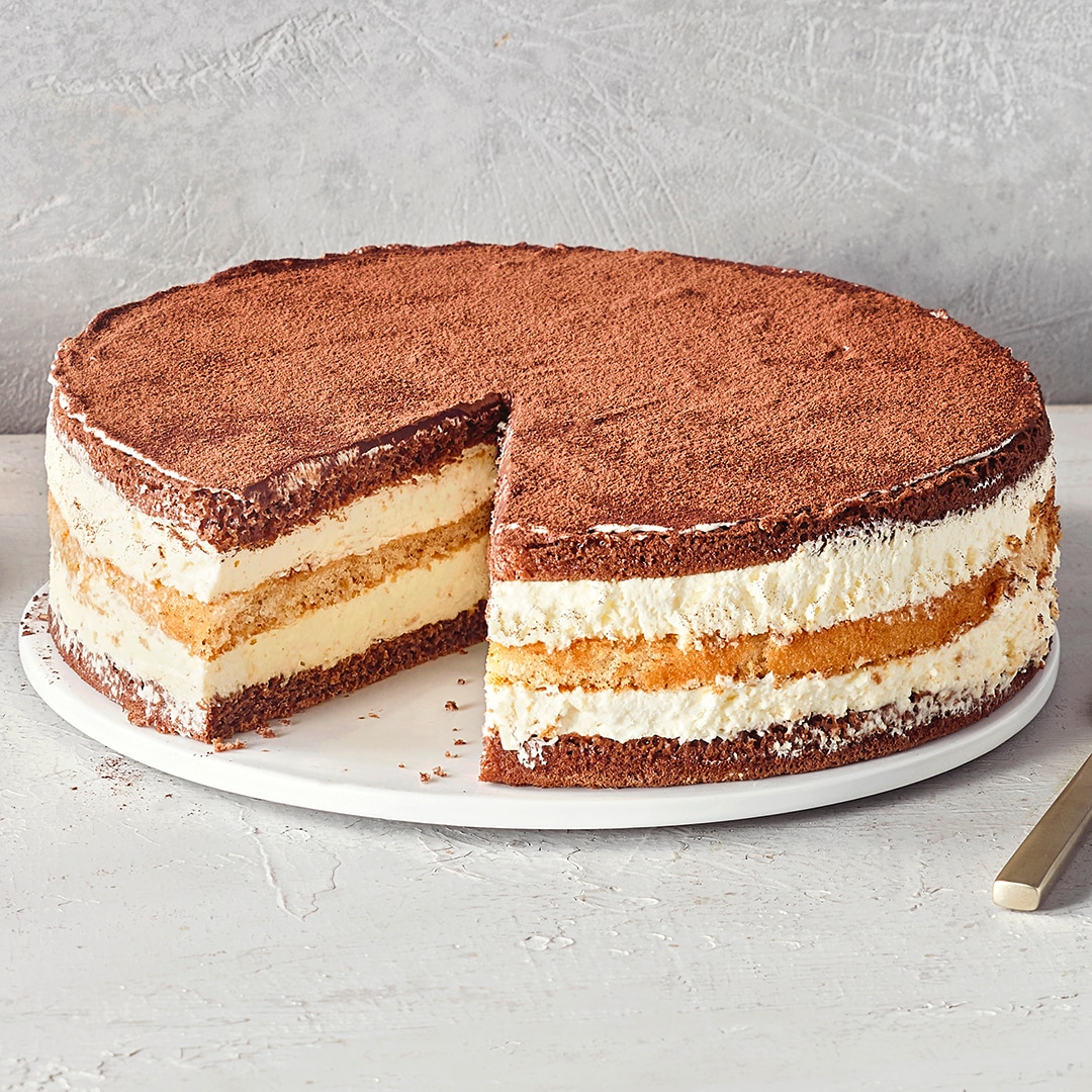 Ein Teller mit einer runden Torte aus braunen Böden und heller Creme