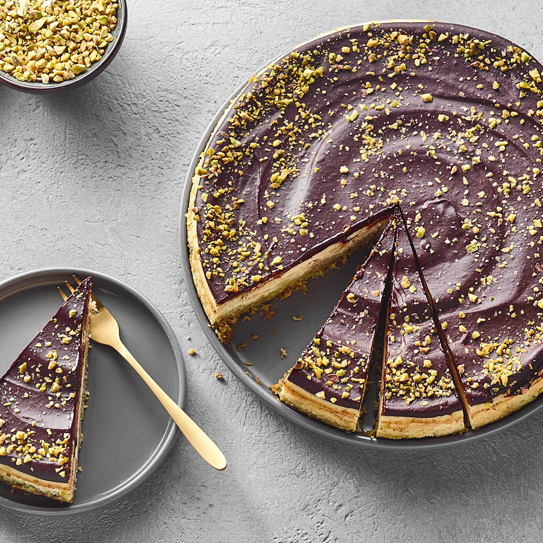 Käsekuchen mit Schokoladenguss und Pistazienstücken.