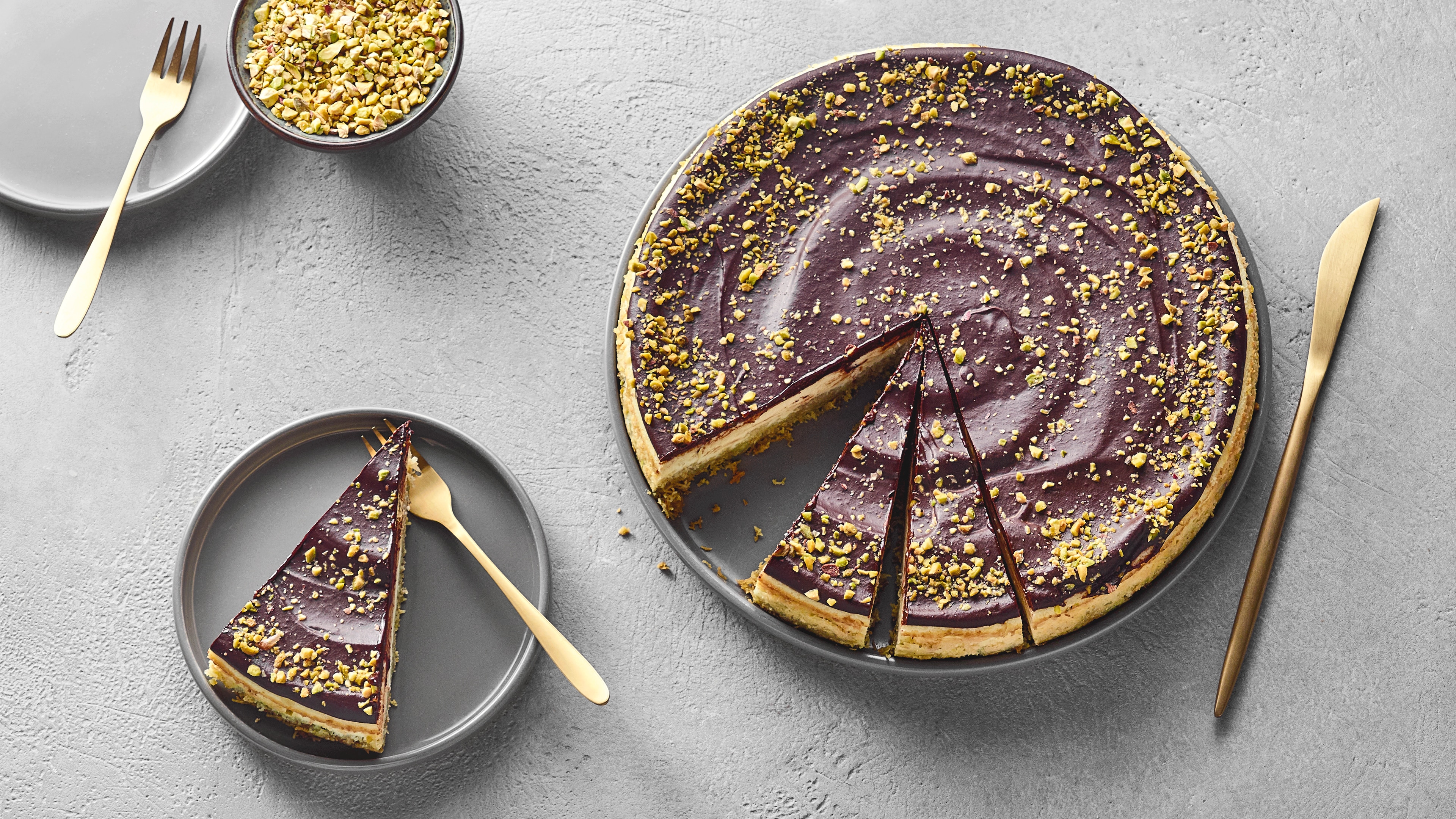 Käsekuchen mit Schokoladenguss und Pistazienstücken.