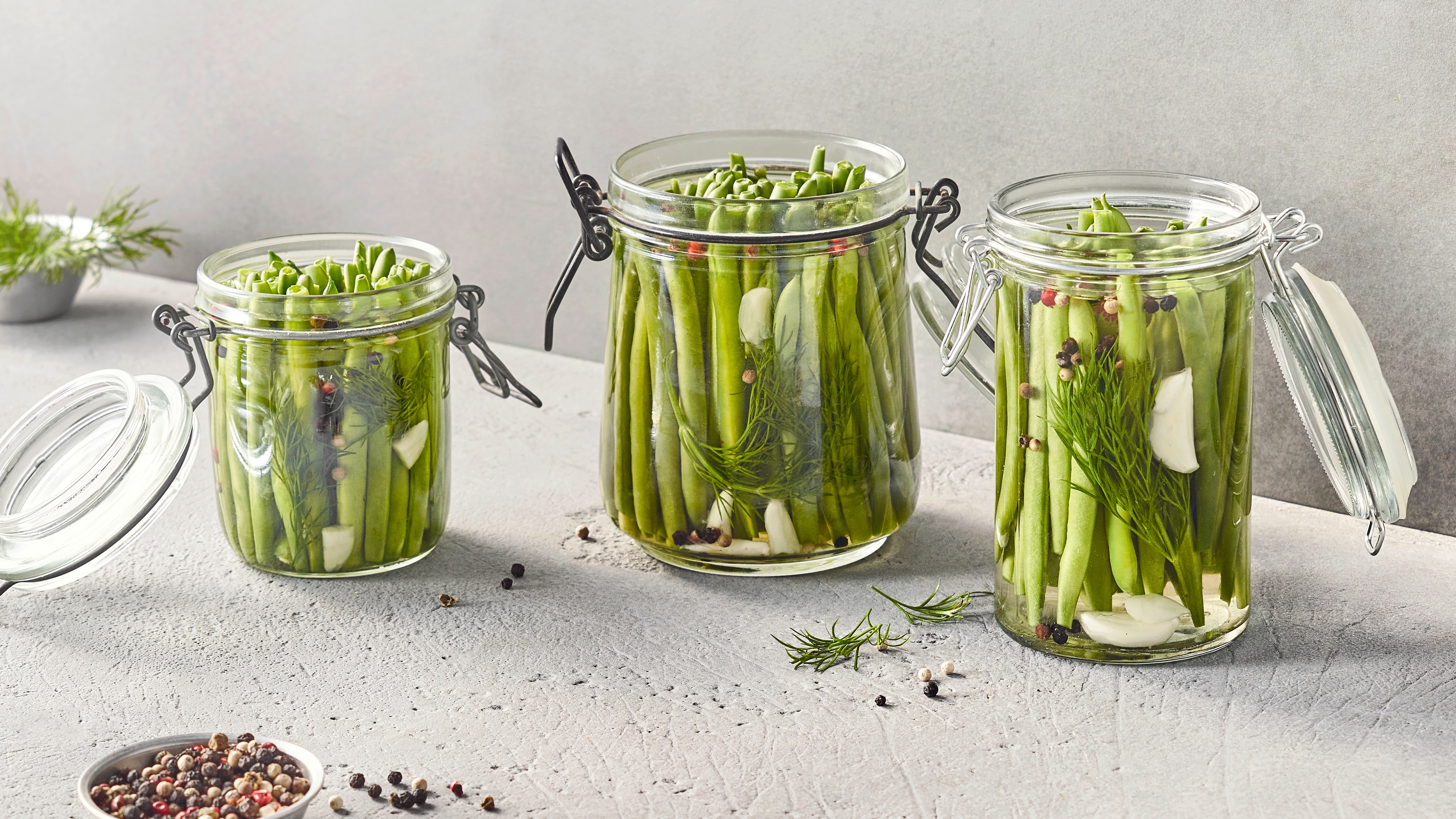Grüne Bohnen mit Flüssigkeit und Pfefferkörnern in Einmachgläsern