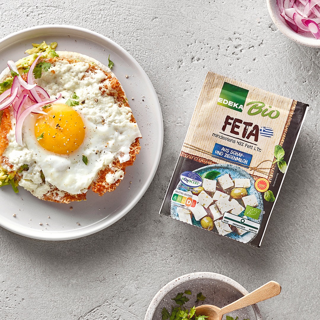 Flaches Brot mit Spiegelei, Feta und Zwiebeln. Rechts daneben EDEKA Bio Feta.