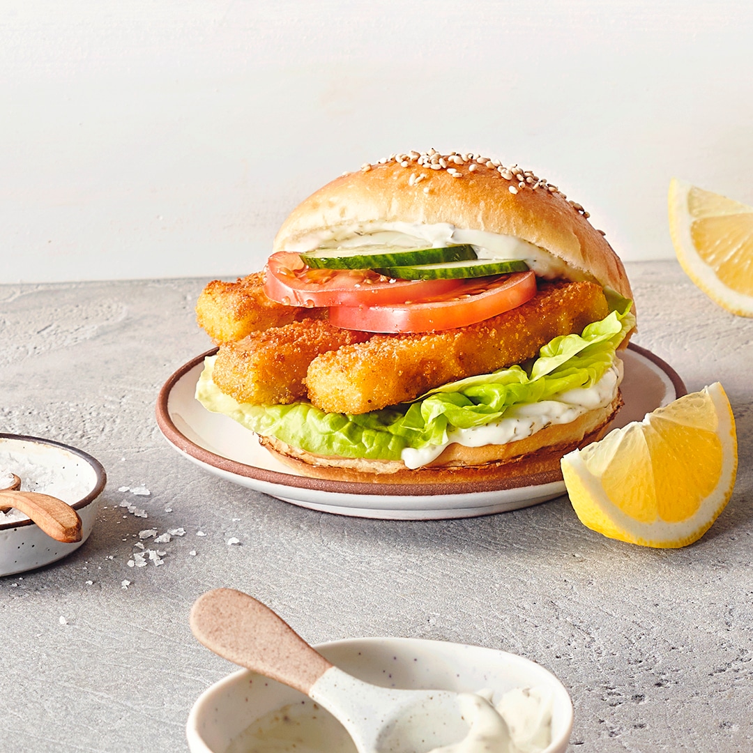 Aufgeklappte Burger mit Salat, Tomaten, Gurken und Fischstäbchen