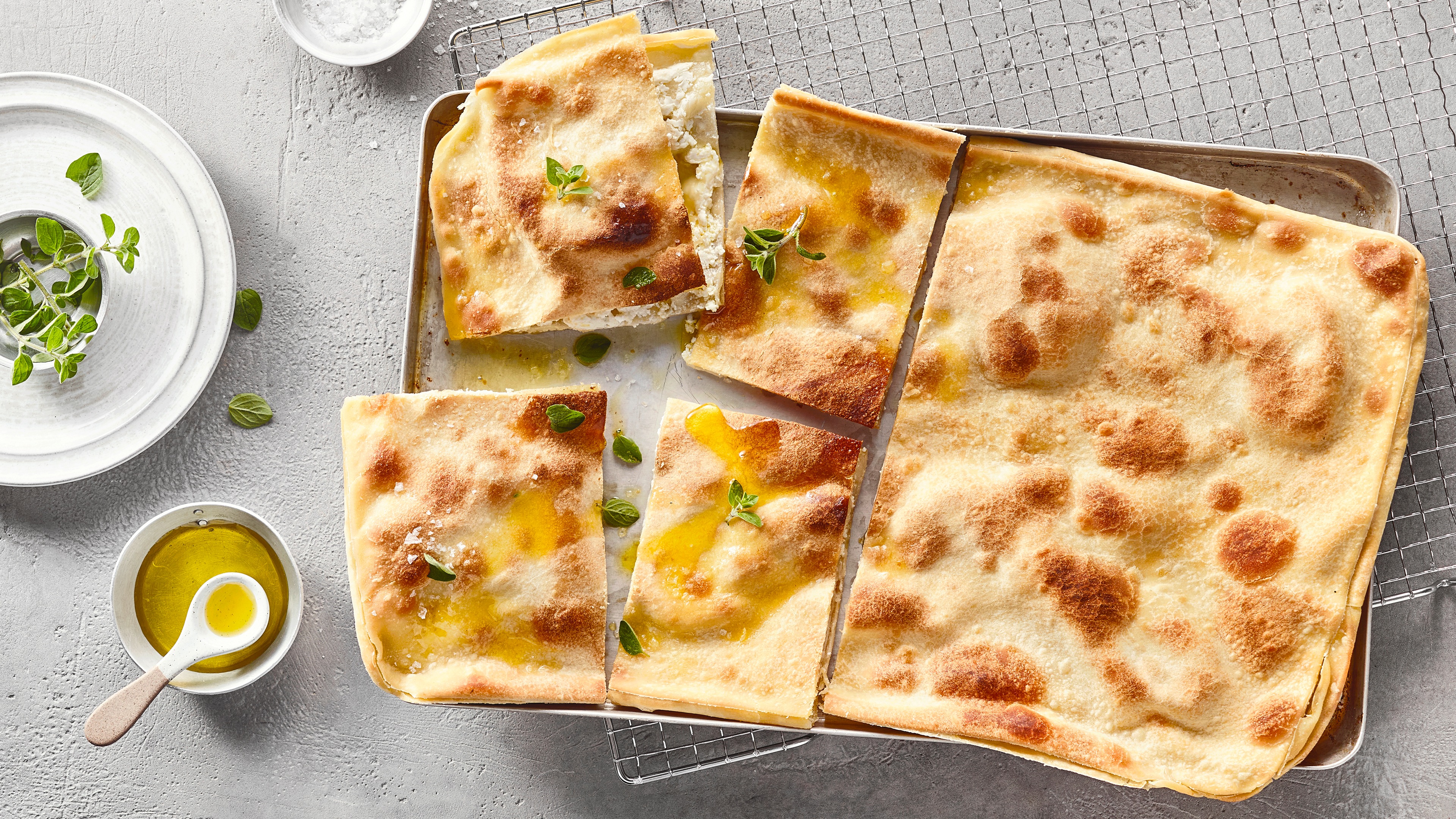 Dünne, rechteckige Brotfladenstücke, daneben ein Schälchen mit Öl