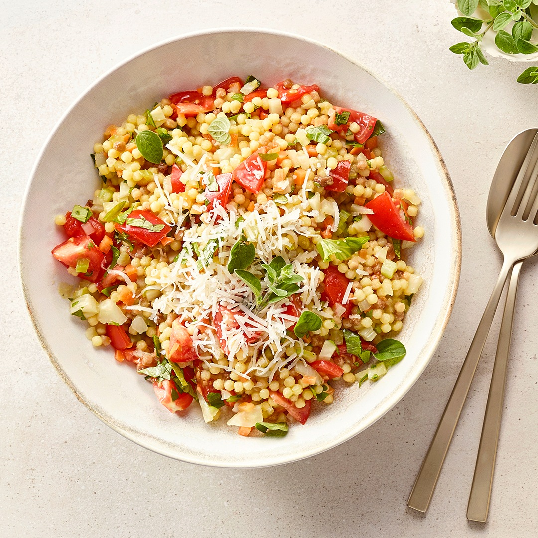 Große Schale mit körnigem Getreide, Tomatenstücken und Kräutern