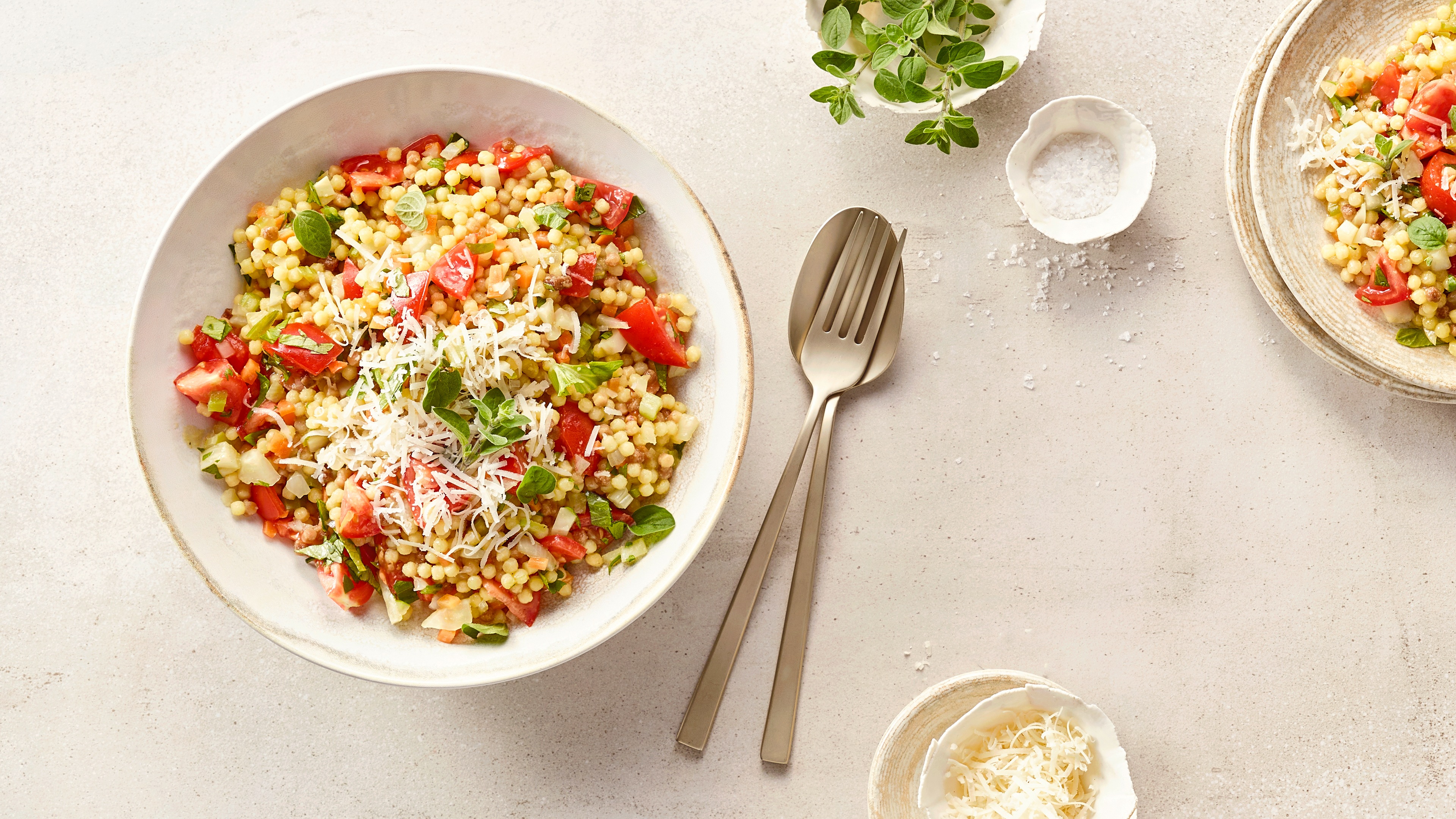 Große Schale mit körnigem Getreide, Tomatenstücken und Kräutern