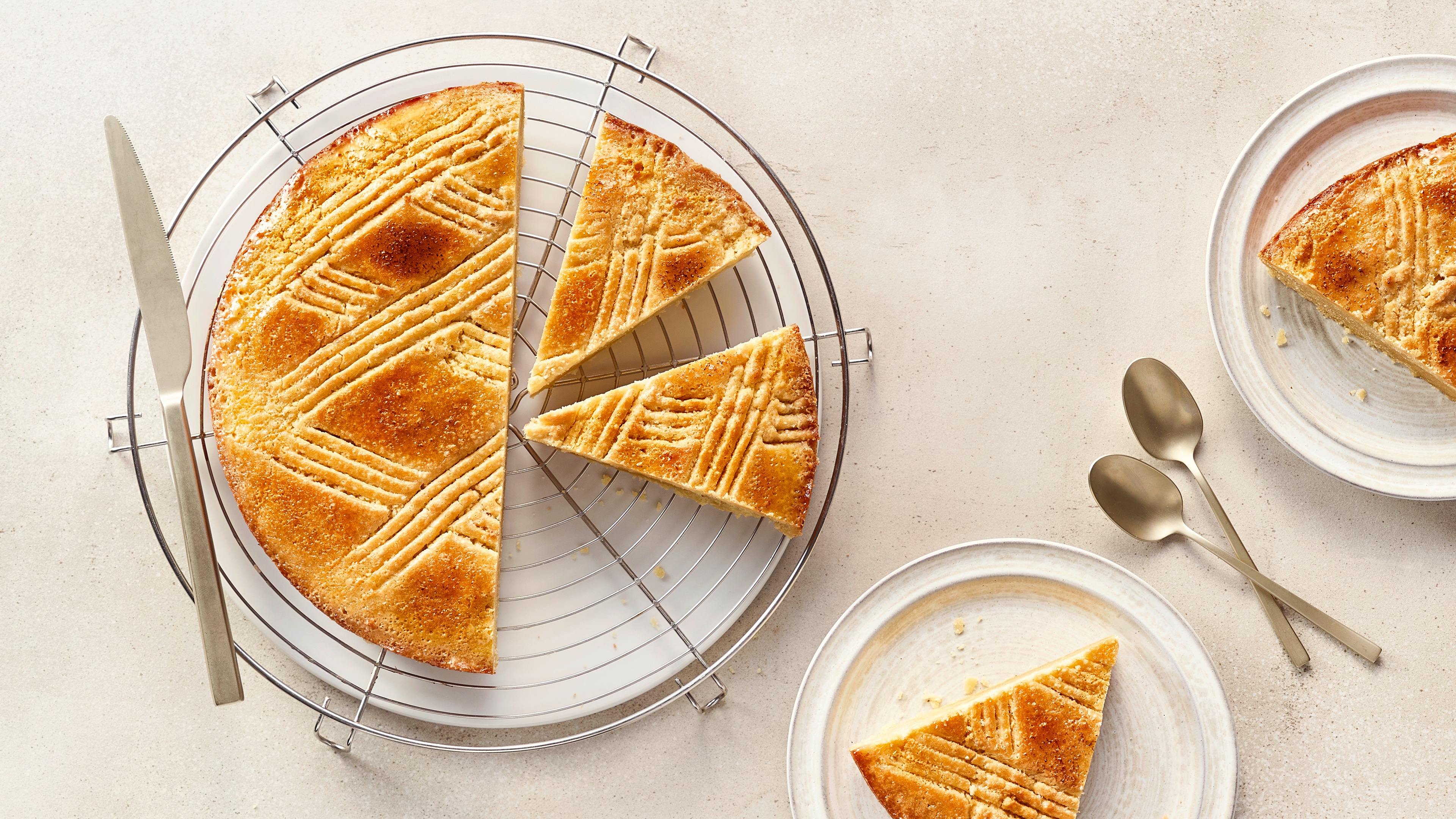Angeschnittener Kuchen mit Muster auf Gitter, daneben Stücke auf kleinen Tellern