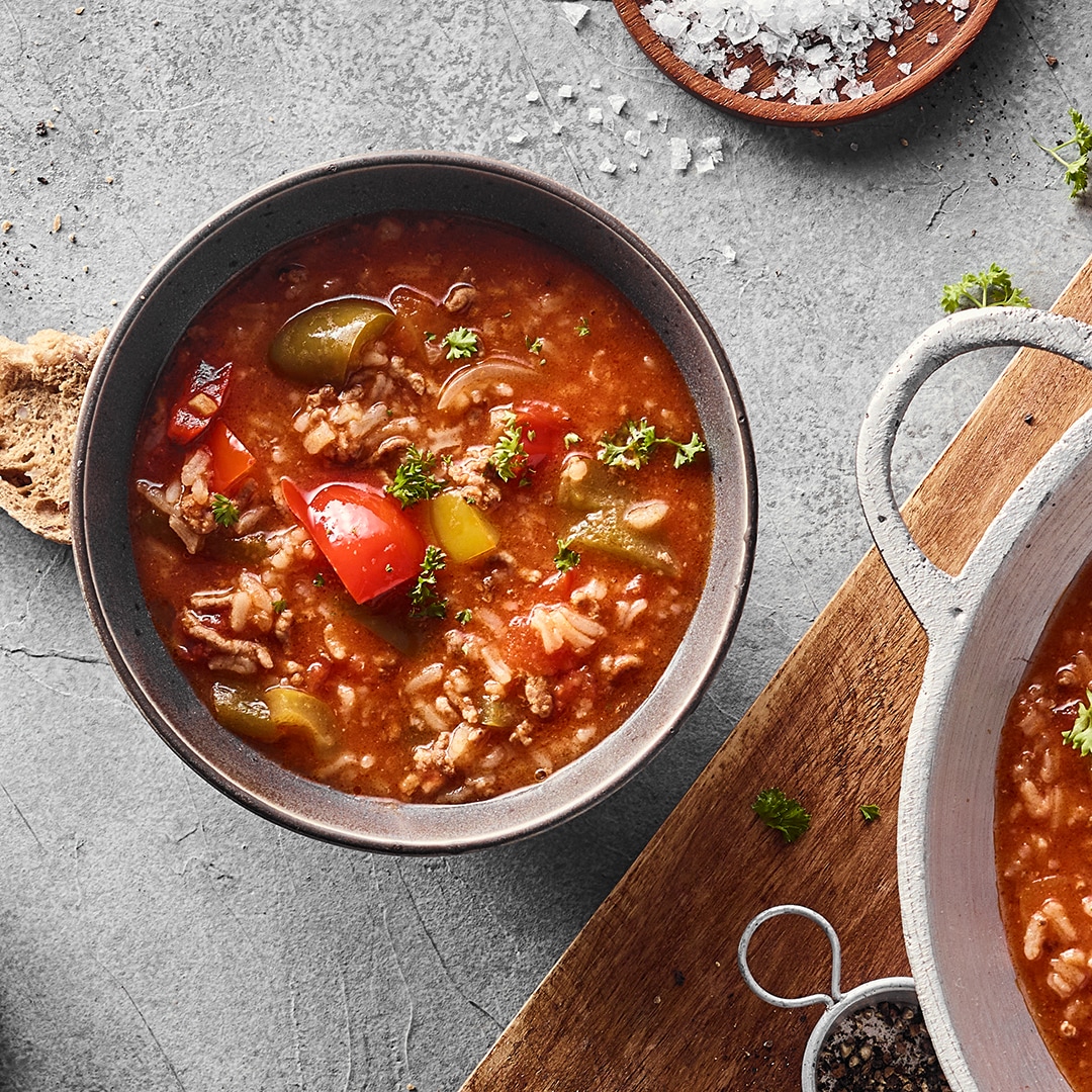 Eine Schale mit roter Suppe mit grünen und roten Paprikastückchen, Hackfleisch und Reis