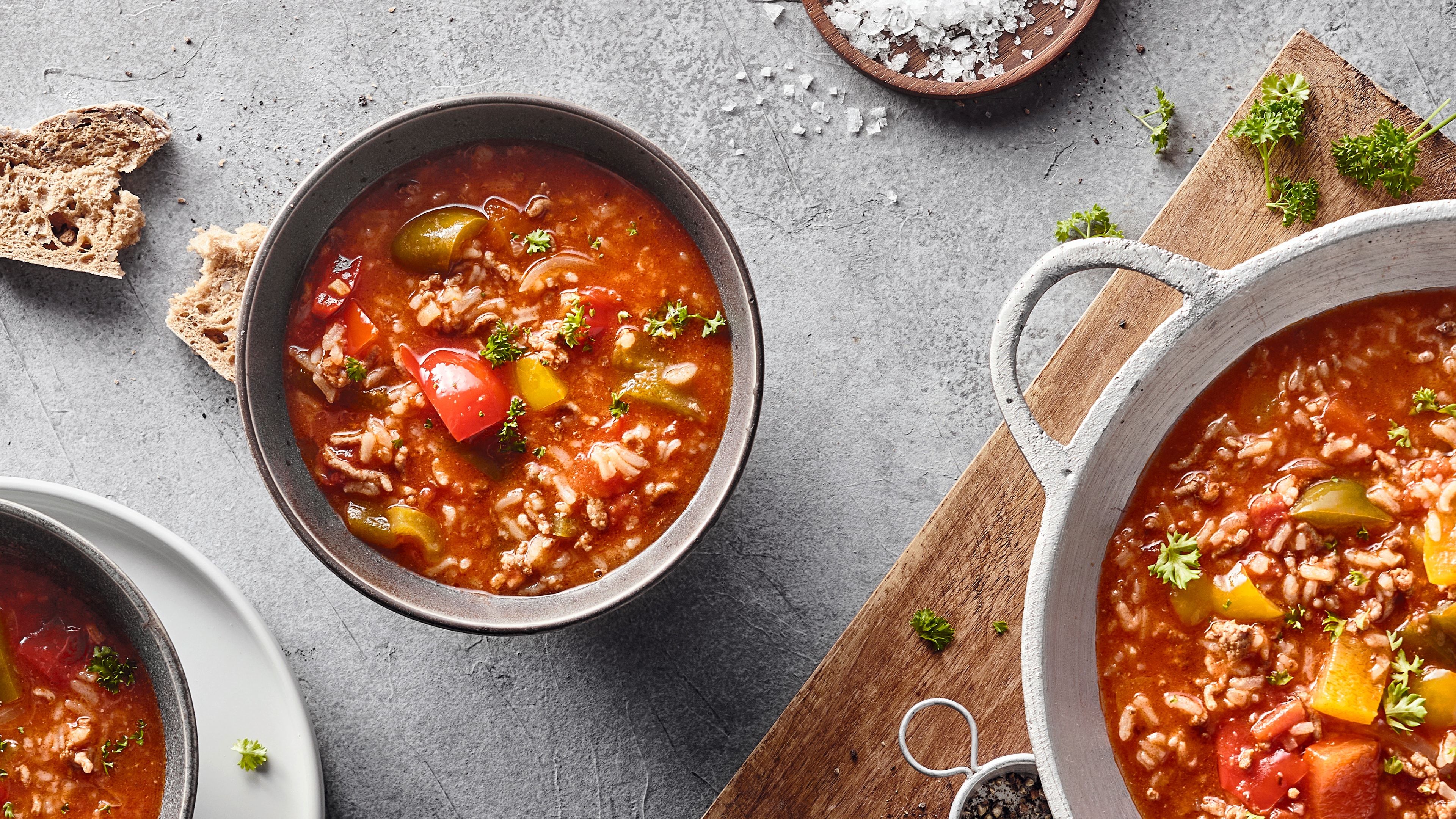 Rezept für gefüllte Paprikasuppe Eine Schale mit roter Suppe mit grünen und roten Paprikastückchen, Hackfleisch und Reis