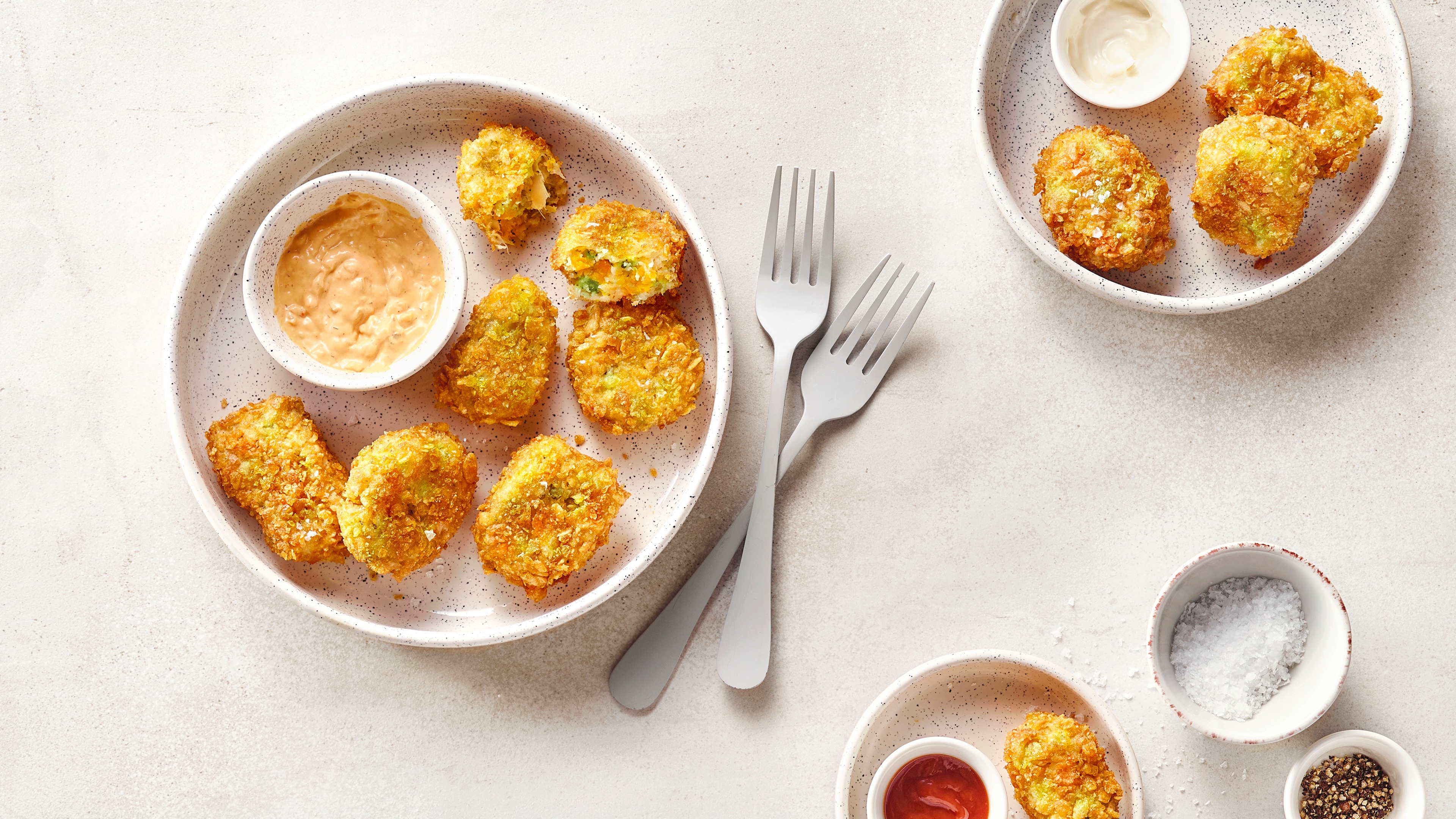 Goldbraun gebratene Nuggets auf Tellern, serviert mit Dip und Gewürzen.