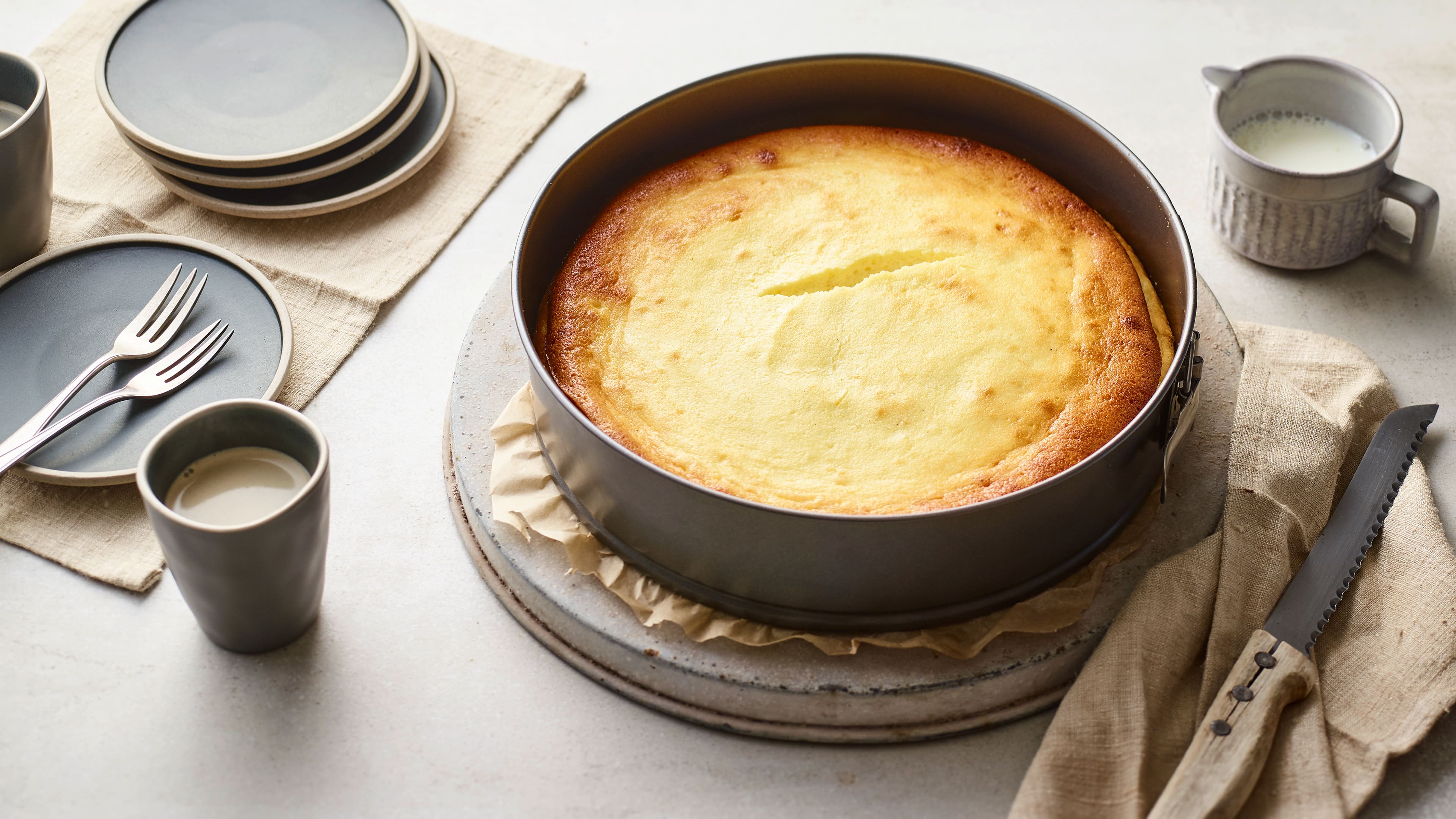 Rezept für glutenfreien Käsekuchen Eine runde Kuchenform, darin ein hellgelber, cremiger Kuchen mit leicht-braunem Rand und einem kleinen mittigen Riss