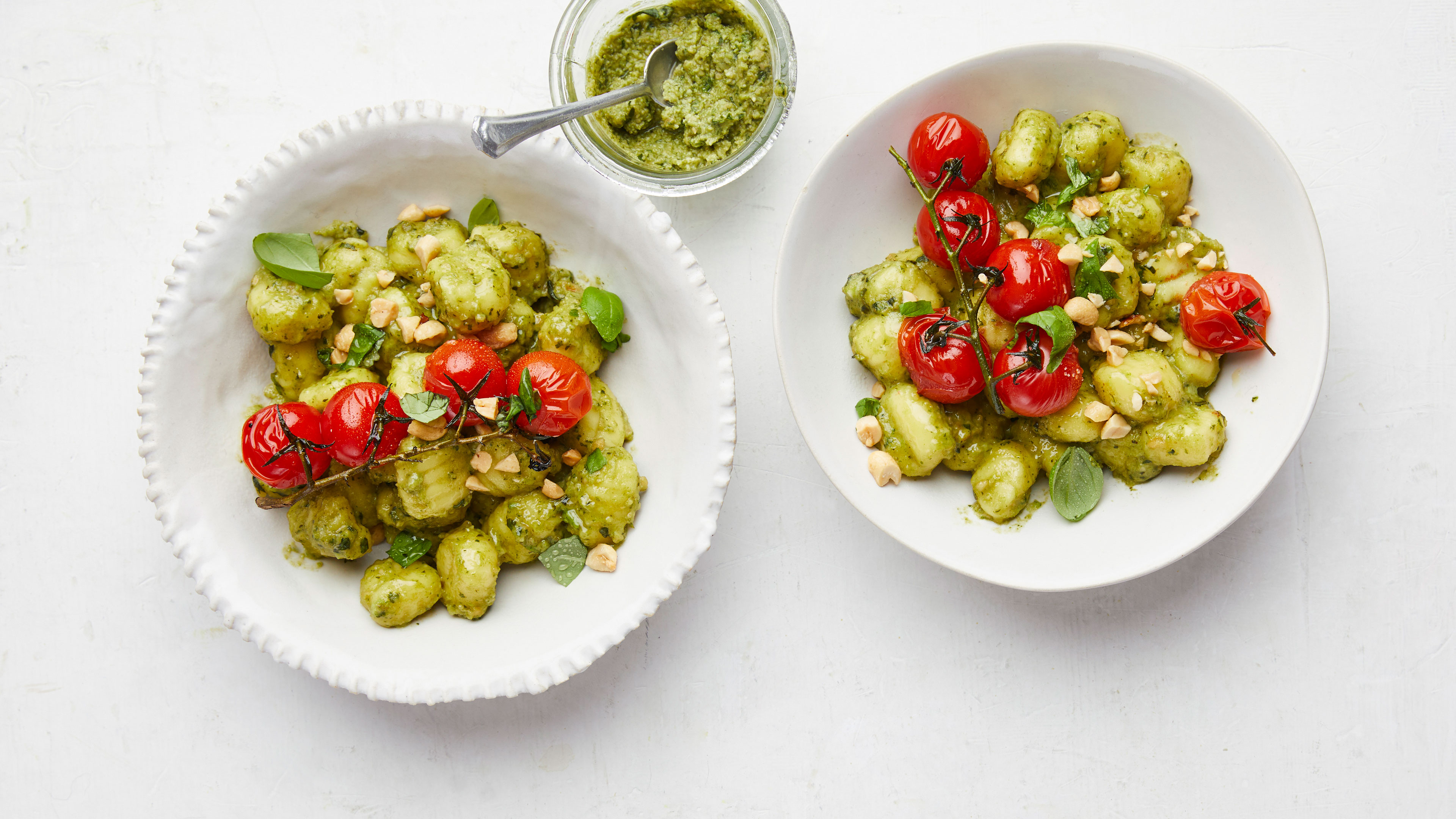 Zwei Teller Gnocchi in grünlicher Soße mit Rispentomaten und Nusstücken