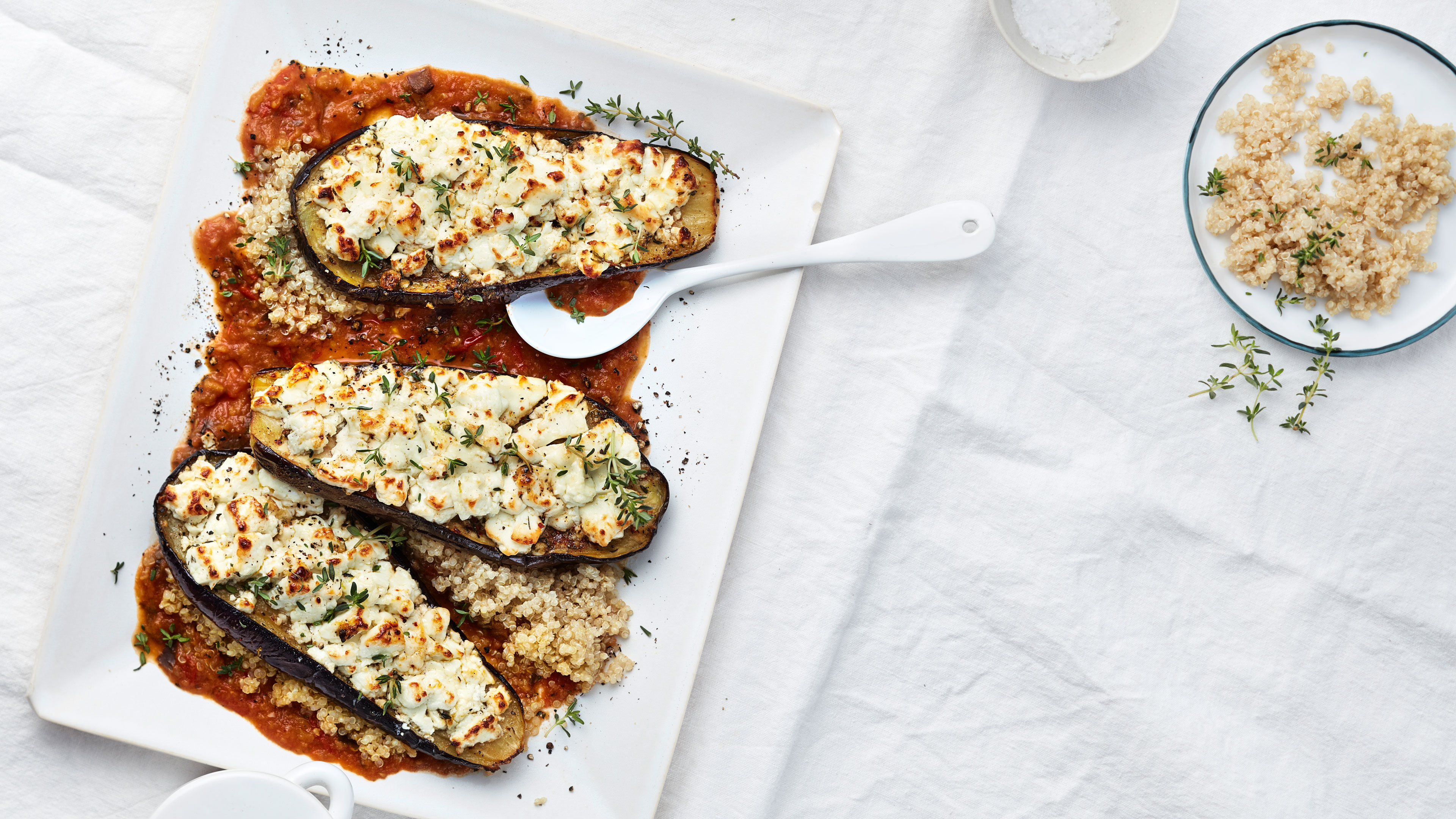 Platte mit Auberginenhälften auf roter Soße und mit Feta gratiniert
