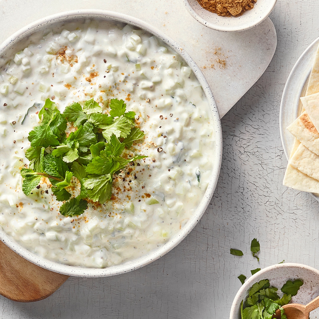 Eine Schüssel mit weißer cremiger Mischung, darin kleine helle Stücke, bestreut mit  Gewürzen und frischen Kräutern.
