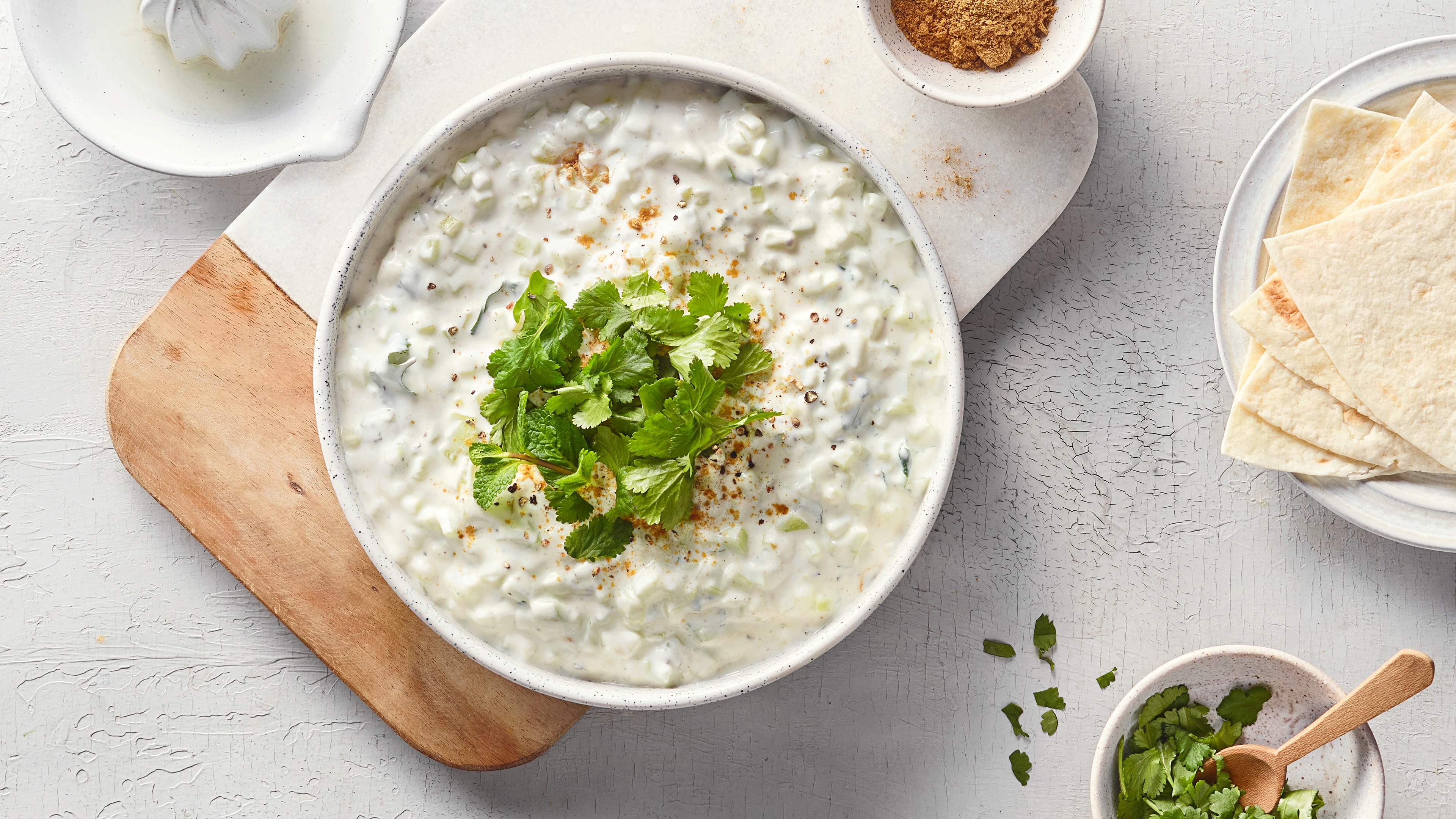 Eine Schüssel mit weißer cremiger Mischung, darin kleine helle Stücke, bestreut mit  Gewürzen und frischen Kräutern.
