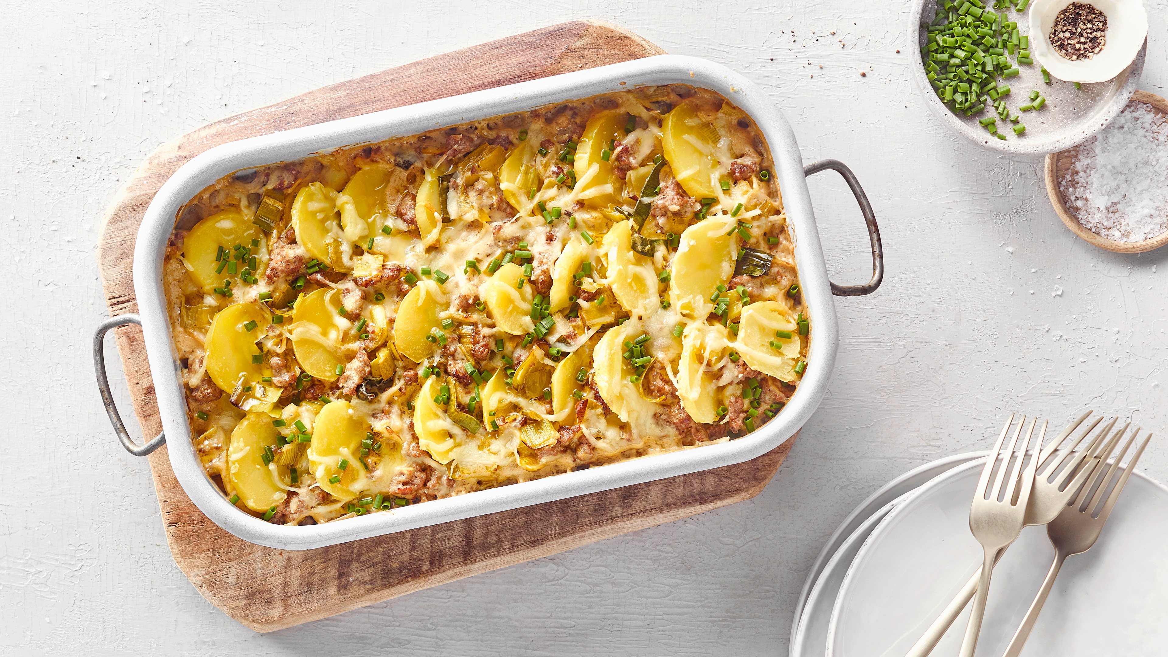 Auflaufform mit Hack, Kartoffelscheiben, überbackenem Käse und Schnittlauch.