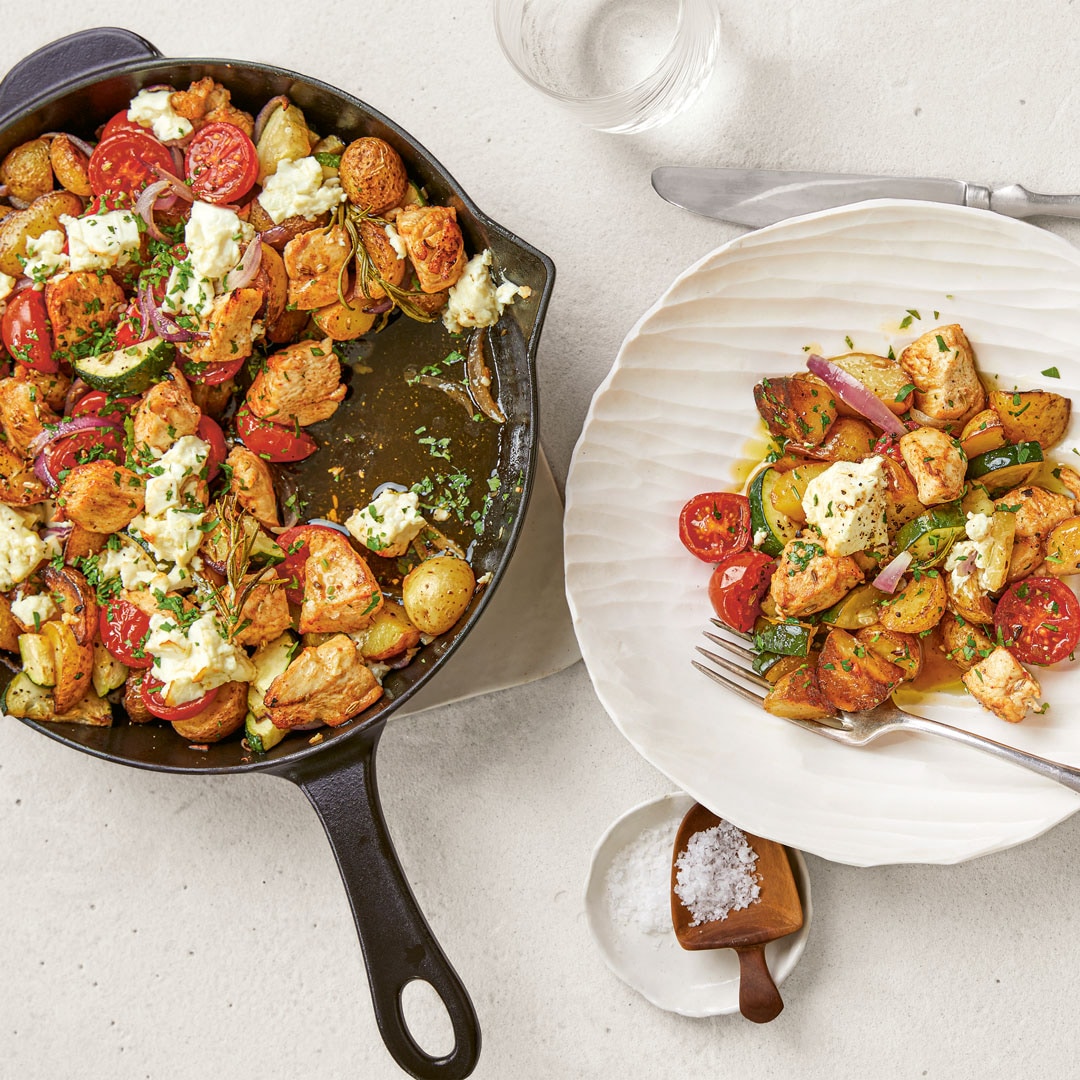 Pfanne mit Kartoffelstücken, Hähnchenstücken, Tomaten und Zucchinischeiben. Daneben ein Teller mit dem Pfannengericht