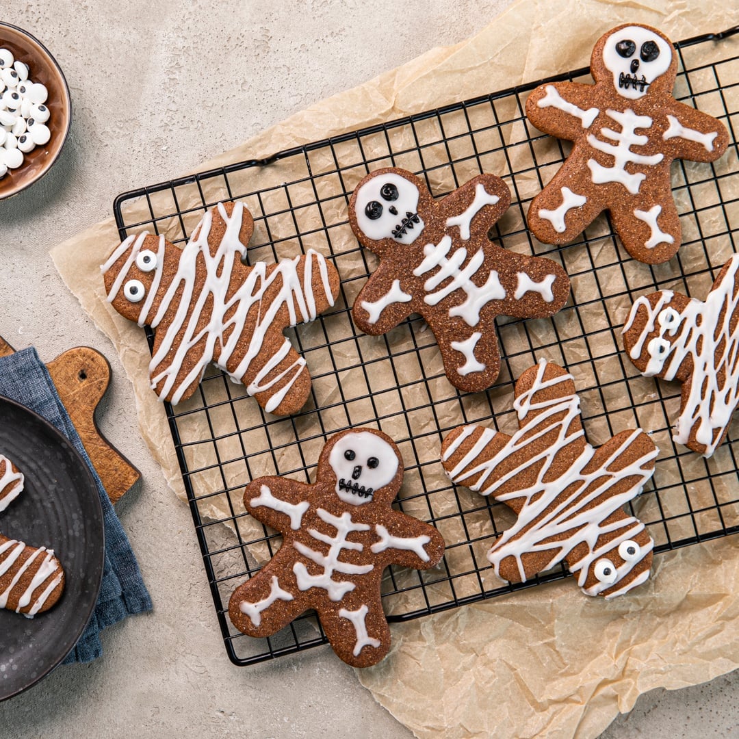 Ein Abkühlgitter mit Lebkuchen-Keks-Männchen, mit weißem und schwarzen Zuckerguss als Mumien und Skelette dekoriert