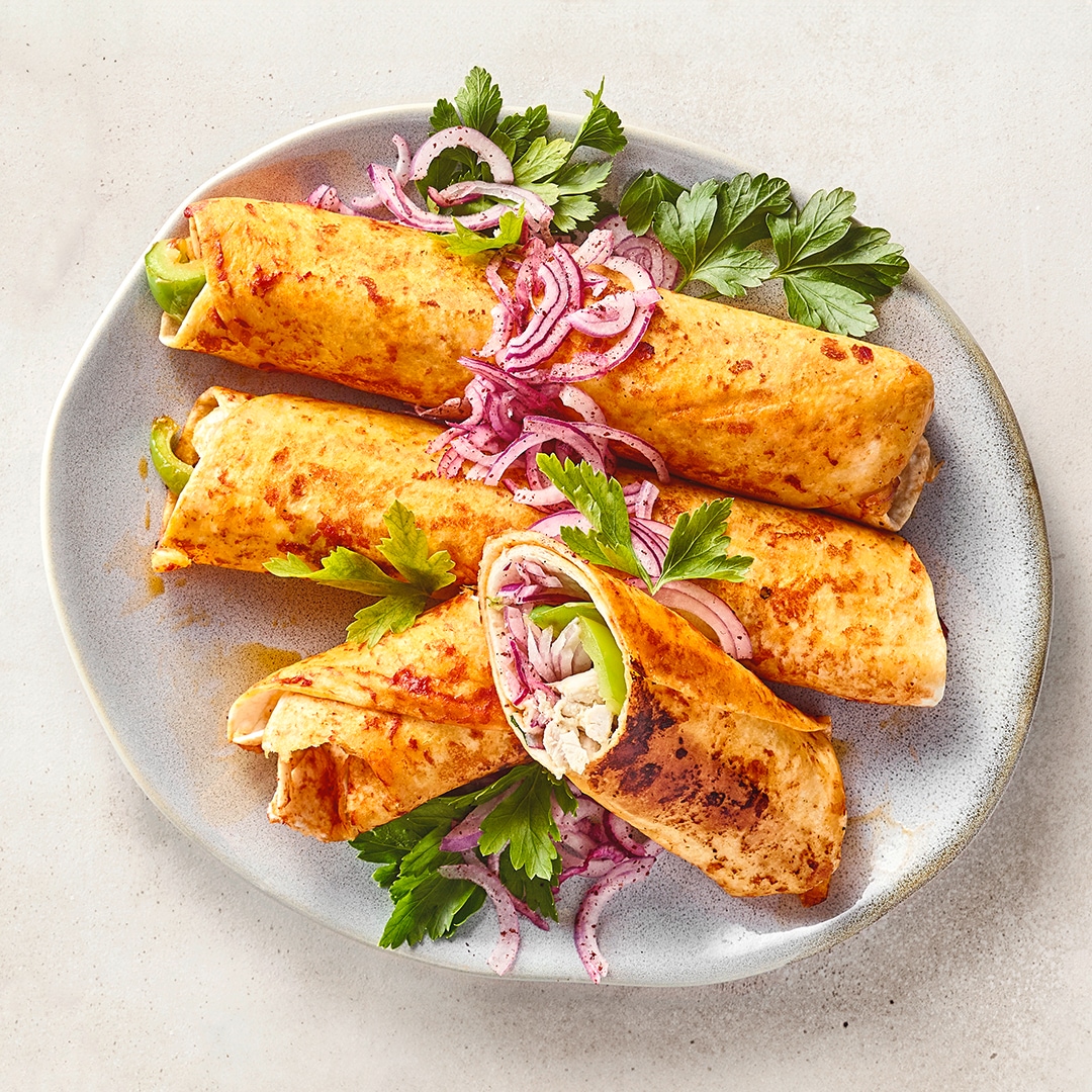 Goldbraun gebratene Wraps mit Füllung, roten Zwiebeln und Petersilie auf einem Teller, serviert mit Salsa.
