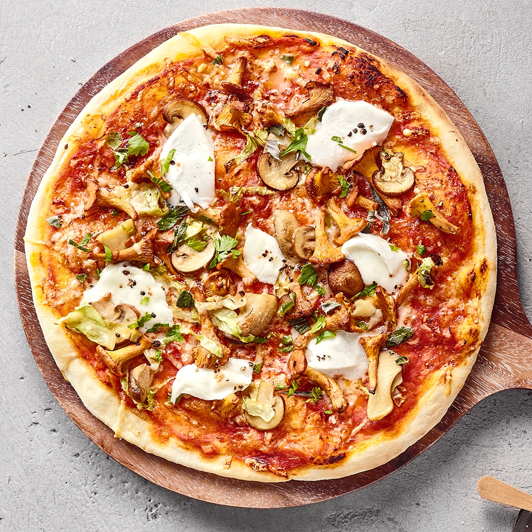 Pizza mit Tomatensoße, Käse, Pilzen und Mozzarella auf einem Holzbrett.